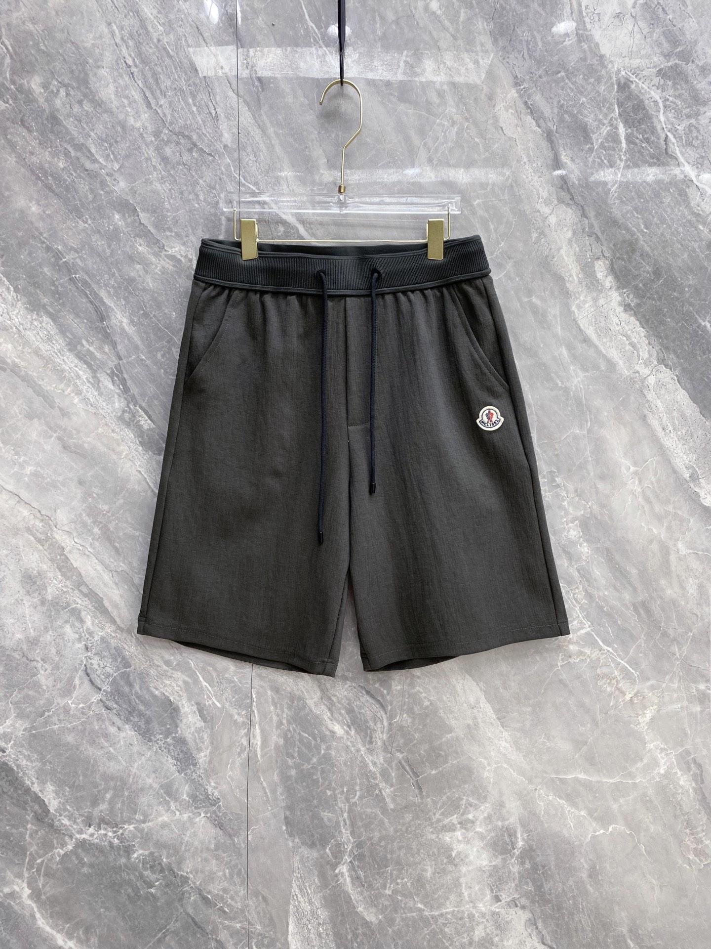 NO:860972,| MONCLER 2026 Spring and Summer New Style Ice-feeling Breathable Casual Shorts A high-end luxury item with a summer cooling buff, embellished with classic brand emblems, low-key highlighting Moncler’s sporty luxury tone. Selected ice-feeling breathable texture fabric, the upper body has a cool feeling, the drape is refreshing and non-sticky to the legs, the loose cut hides the flesh and is neat. Ribbed waist + drawstring design, adapts to a variety of body shapes, and has no sense of restraint in daily wear.  The practical pockets on both sides take into account both appearance and practicality. Available in four colors: white/beige/dark gray/black, you can easily control a variety of styles including casual, sophisticated and commuting, and can provide you with refreshing outfits throughout the summer. Size 48~56, Moncler, Moncler, shorts,19860909| MONCLER 蒙口 盟可睐 2026春夏新款 冰感透气休闲短裤 自带夏日凉感buff的高奢刚需单品,经典品牌徽章点缀,低调彰显盟可睐的运动奢调 甄选冰感透气肌理面料,上身自带凉感,垂坠清爽不粘腿,宽松剪裁藏肉又利落 罗纹腰头+抽绳设计,适配多种身形,日常穿零束缚感 双侧实用口袋兼顾颜值与实用性,白/米灰/深灰/黑四色可选,轻松驾驭休闲、轻熟、通勤多种风格,承包你整个夏天的清爽穿搭 码数48~56,,Moncler,Moncler,shorts,,Men's clothing