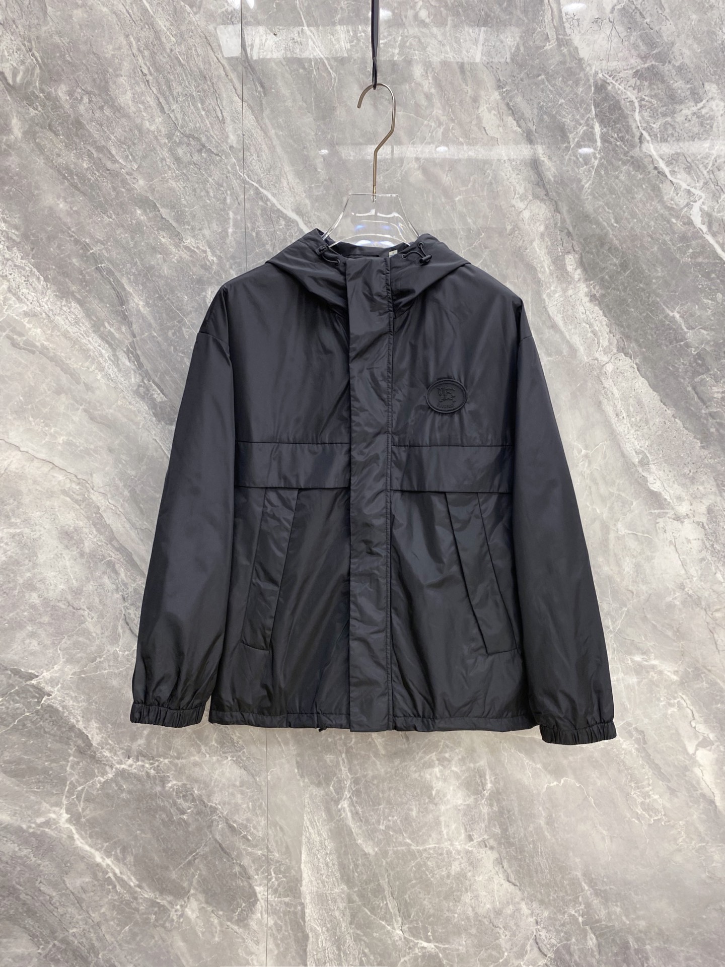 NO:956508,Burberry 2026 Early Autumn Men's Hooded Windproof Jacket, pure black, high-end and versatile, suitable for both business and leisure. Made of light and wrinkle-resistant windproof fabric, it has a stiff and not soft feeling; the detachable and adjustable drawstring hood can cope with windy weather. The fly zipper + rainproof and windproof hidden placket double-layer design, the leather oval knight logo on the chest is low-key and luxurious.  Three-dimensional divided large pockets for practical storage; elastic cuffs at the hem to lock in wind and keep warm. Loose fit and short version, suitable for wearing alone or layered with a down jacket. Size M-3XL,,burberry,burberry,jackets & coats,down jacket,hats,19860909Burberry 巴宝莉 2026早秋男士连帽防风夹克,纯黑高级百搭,商务休闲通吃. 轻薄抗皱防风面料,自带挺括感不软塌；可拆卸调节抽绳连帽,应对大风天气. 门襟拉链+挡雨防风暗门襟双层设计,胸口皮质椭圆形骑士标低调轻奢. 立体分割大插袋,储物实用；松紧收口袖口下摆,锁风保暖.宽松合身短款版型,单穿、内搭羽绒服都合适 码数M-3XL,,burberry,burberry,jackets & coats,down jacket,hats,,Men's clothing