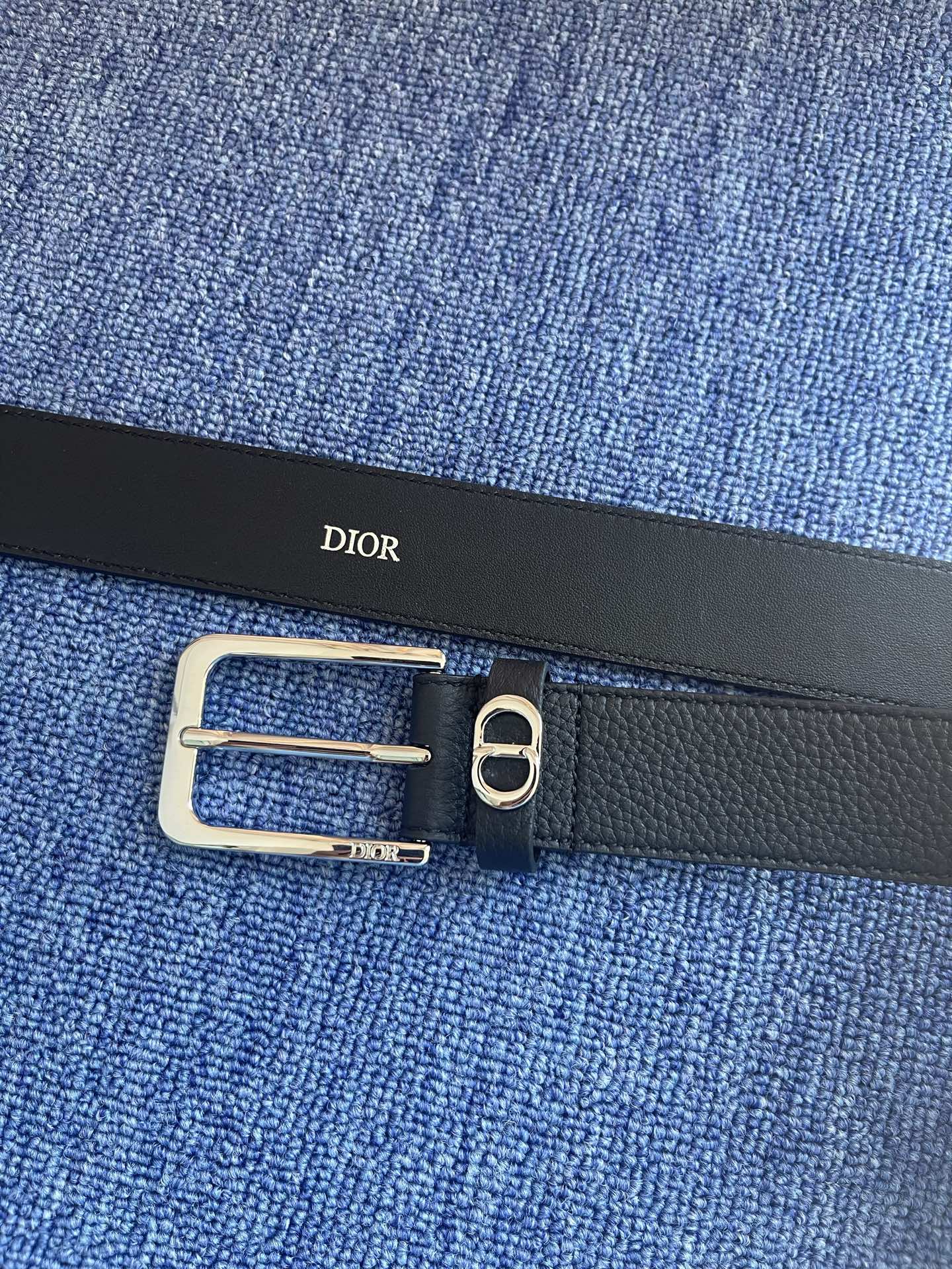 采用黑色粒面牛皮革精心制作，饰以镌刻有 Dior 的针扣和黑色金属覆层铜合金 CD Icon 标志腰带环