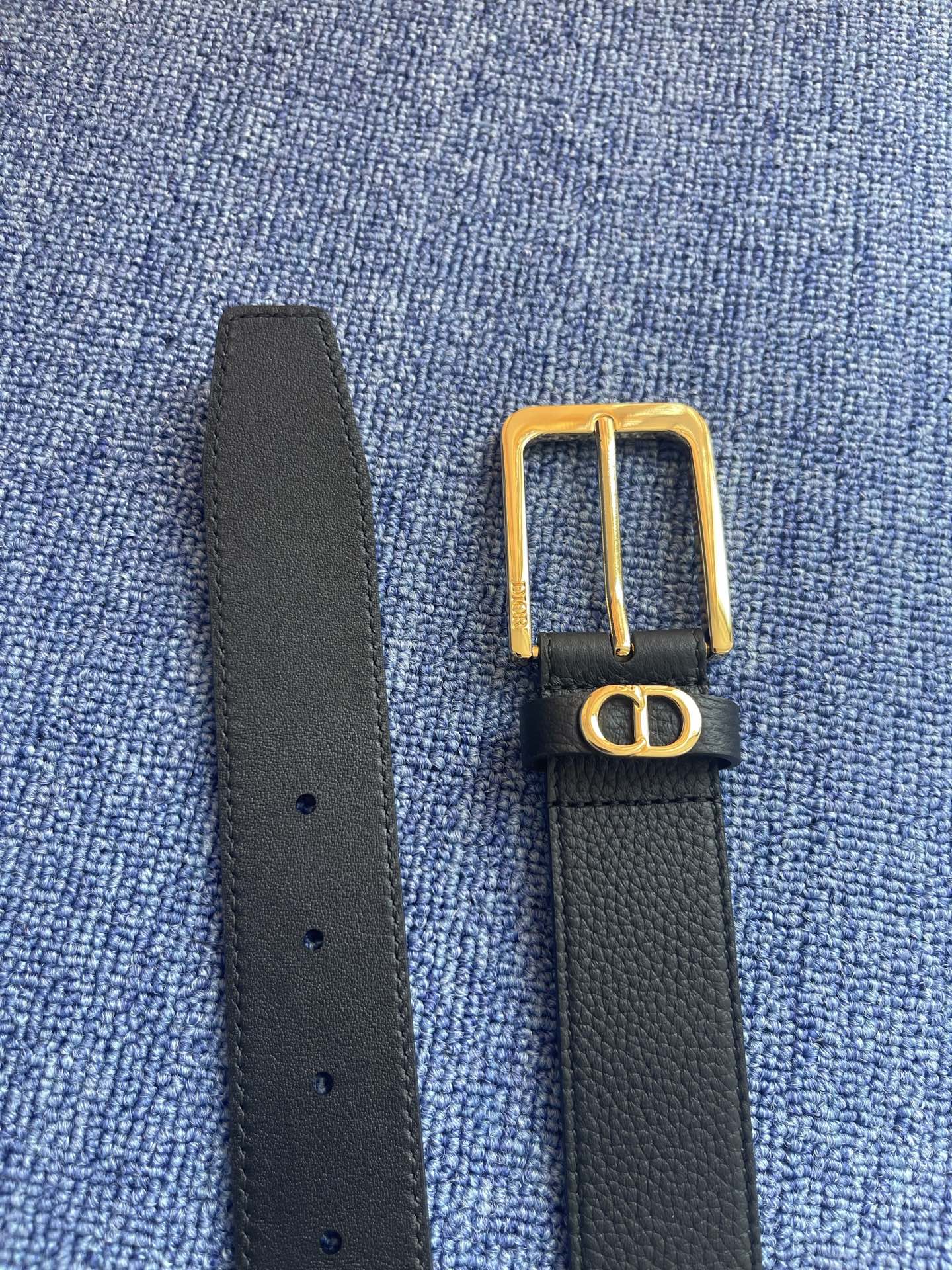 采用黑色粒面牛皮革精心制作，饰以镌刻有 Dior 的针扣和黑色金属覆层铜合金 CD Icon 标志腰带环