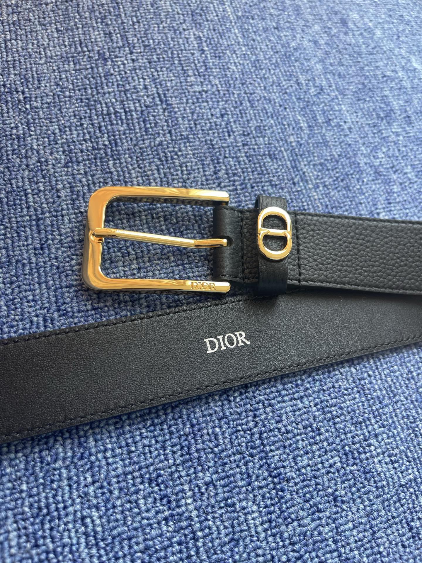 采用黑色粒面牛皮革精心制作，饰以镌刻有 Dior 的针扣和黑色金属覆层铜合金 CD Icon 标志腰带环