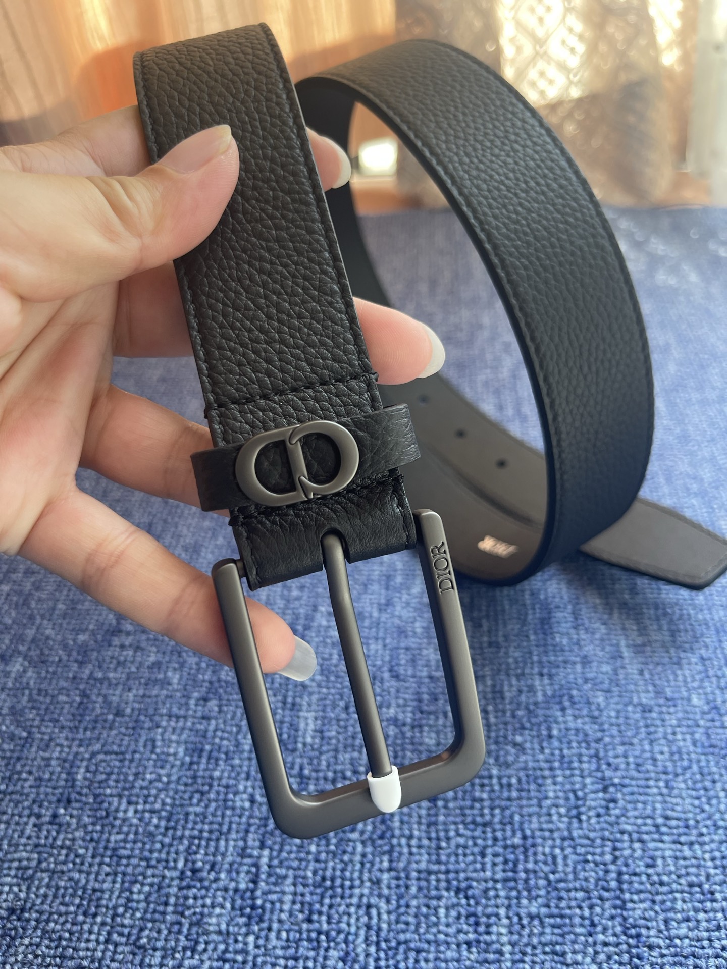 采用黑色粒面牛皮革精心制作，饰以镌刻有 Dior 的针扣和黑色金属覆层铜合金 CD Icon 标志腰带环