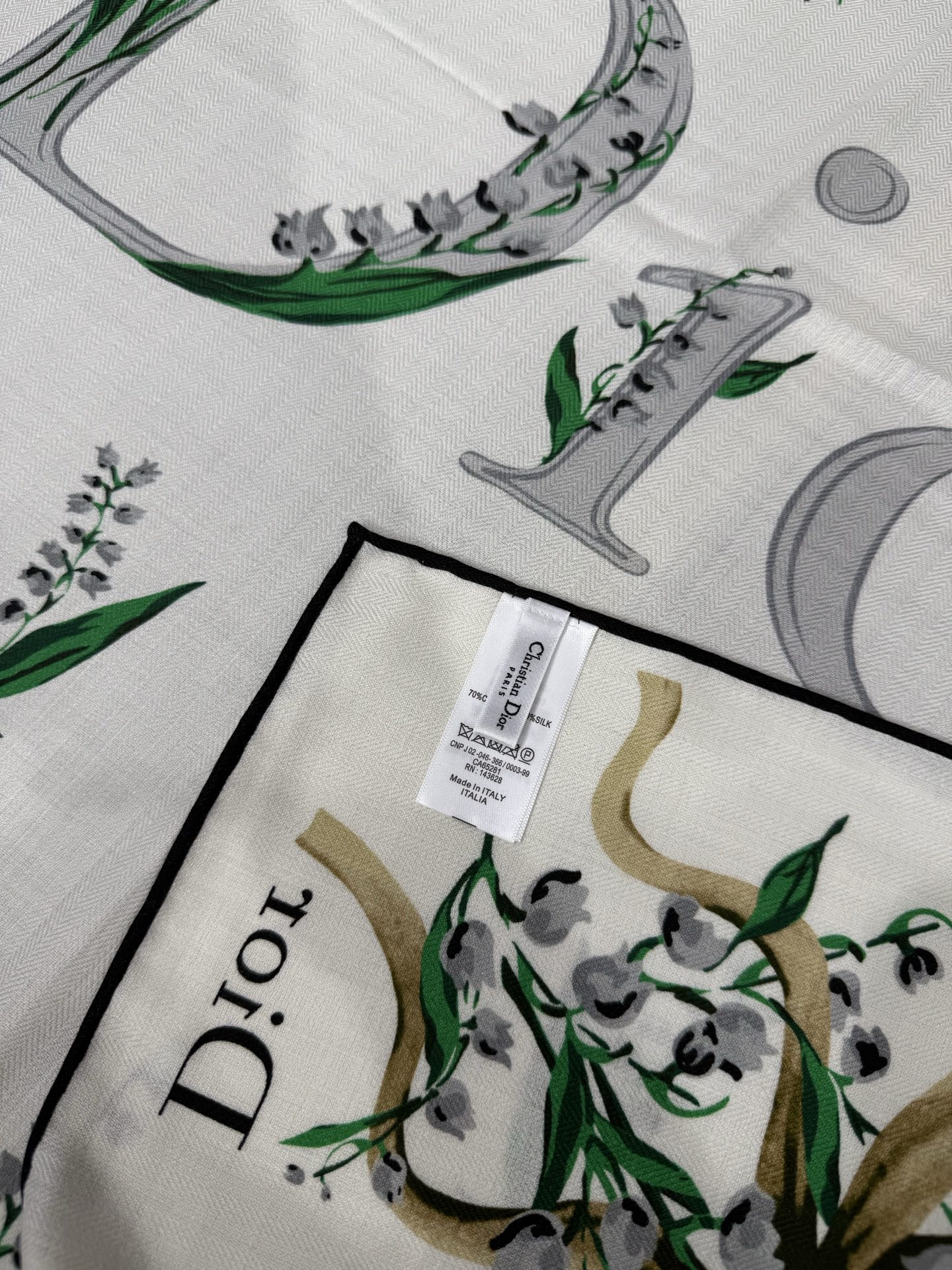 26年秋冬新品这款140丝绒披肩采用了Dior标志性的铃兰（Lily of the Valley）印花，白底绿叶搭配金色