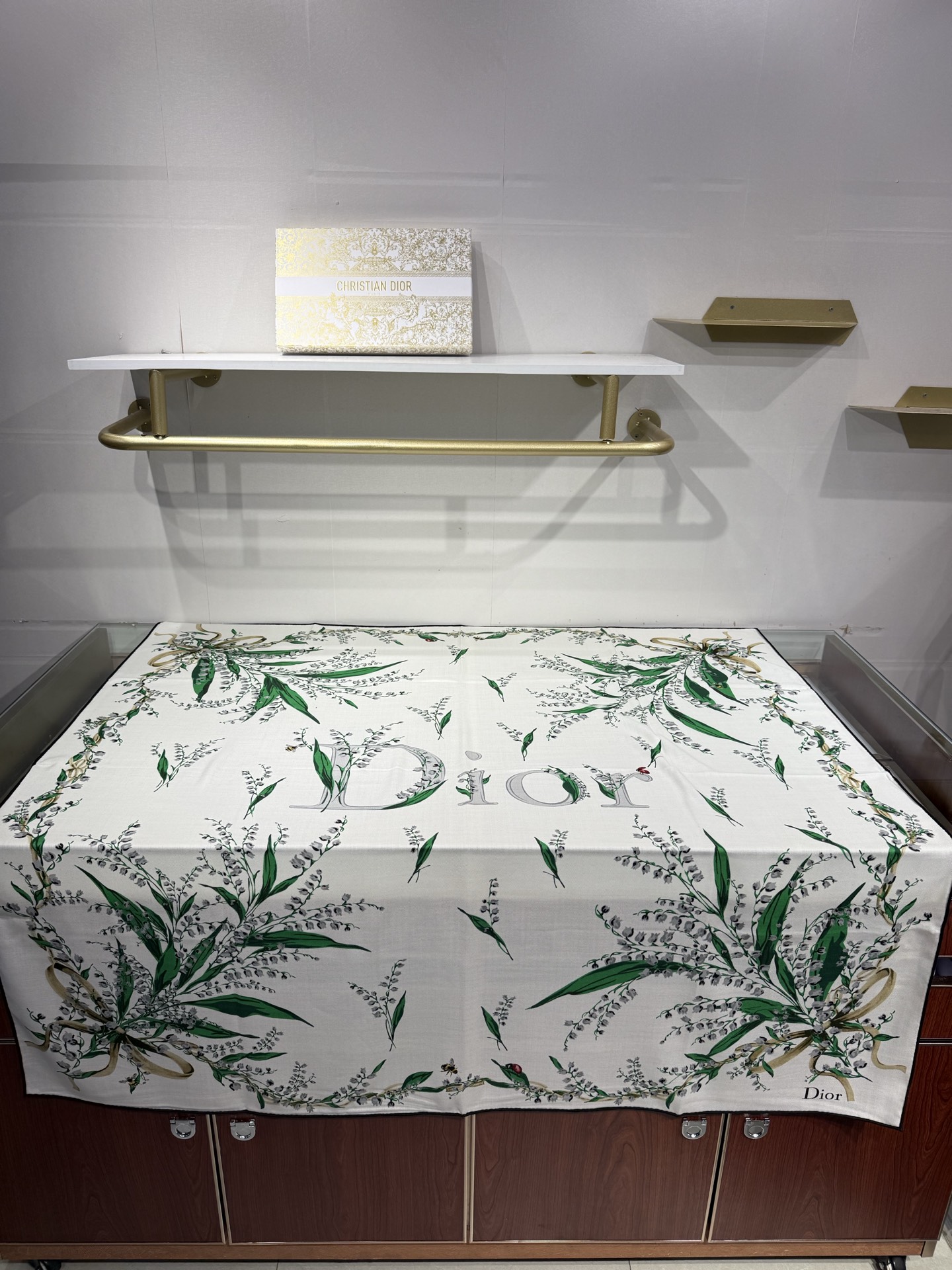 26年秋冬新品这款140丝绒披肩采用了Dior标志性的铃兰（Lily of the Valley）印花，白底绿叶搭配金色