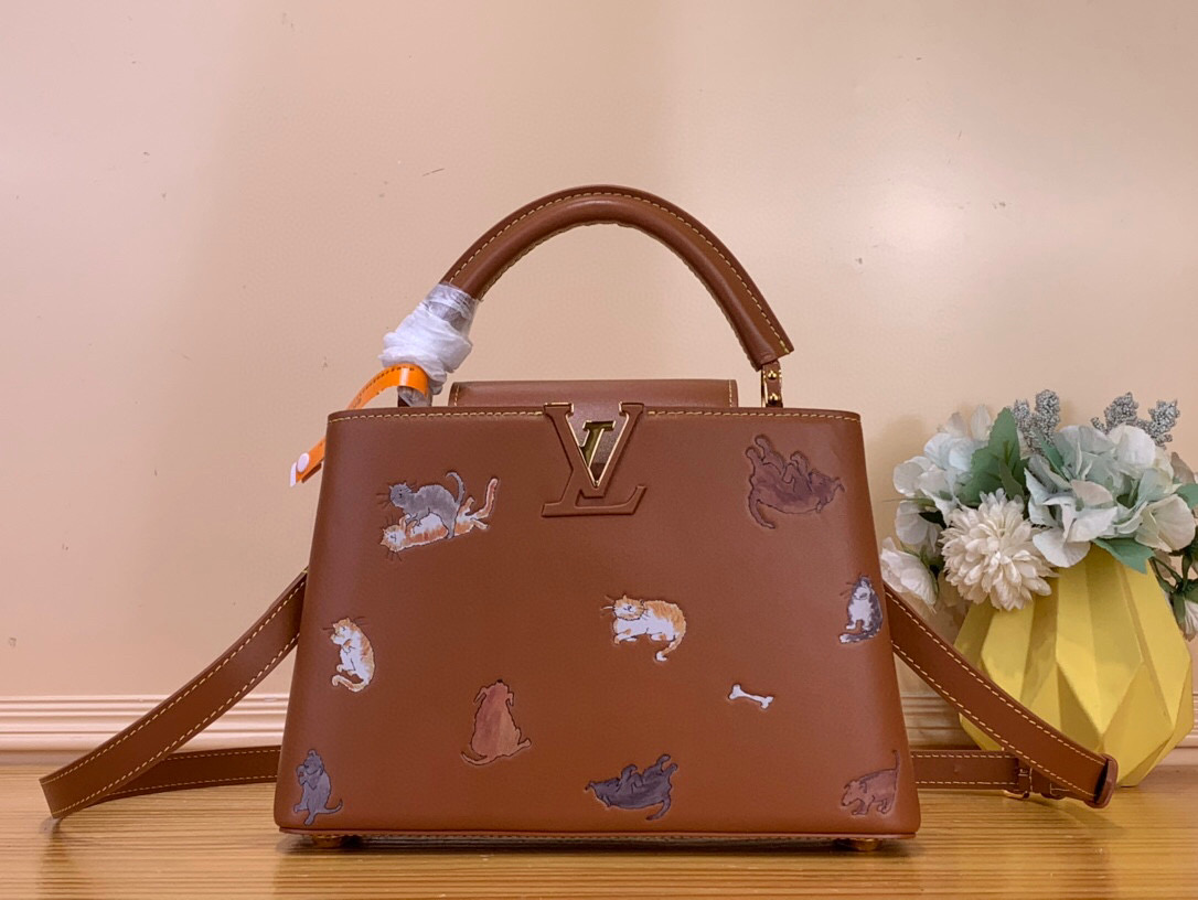 NO:581646,The top original item [CAUCINES BB handbag] m25874 brown/cat LV Travels With series renders the Caucines BB Hr handbag in classic colors, adding smart details with hand-drawn cat illustrations by fashion icon and artist Grace Coddington. This replica version originates from the first collaboration in 2019, with LV letters on the cow leather body. The flip cover can be folded in or out, and the detachable long shoulder strap allows for multiple carrying methods.  Dimensions 17.3 x 9 x 27 cm 122121330 (height x width x length),,louis vuitton,cowhide19860909顶级原单【CAUCINES BB 手袋】 m25874 棕色/猫咪 LV Travels With 系列为 Caucines BB Hr手袋渲染经典色调,以时尚偶像兼艺术家 Grace Coddington 手绘的猫咪插画增添灵动细节.该复刻版本源自 2019 年的首次合作,为牛皮革包身搭配 LV 字母.翻盖适宜内收或外置,可拆卸长肩带实现多种背携方式. 尺寸17.3 x 9 x 27 厘米 122121330 (高 x 宽 x 长度),,louis vuitton,cowhide,Bag