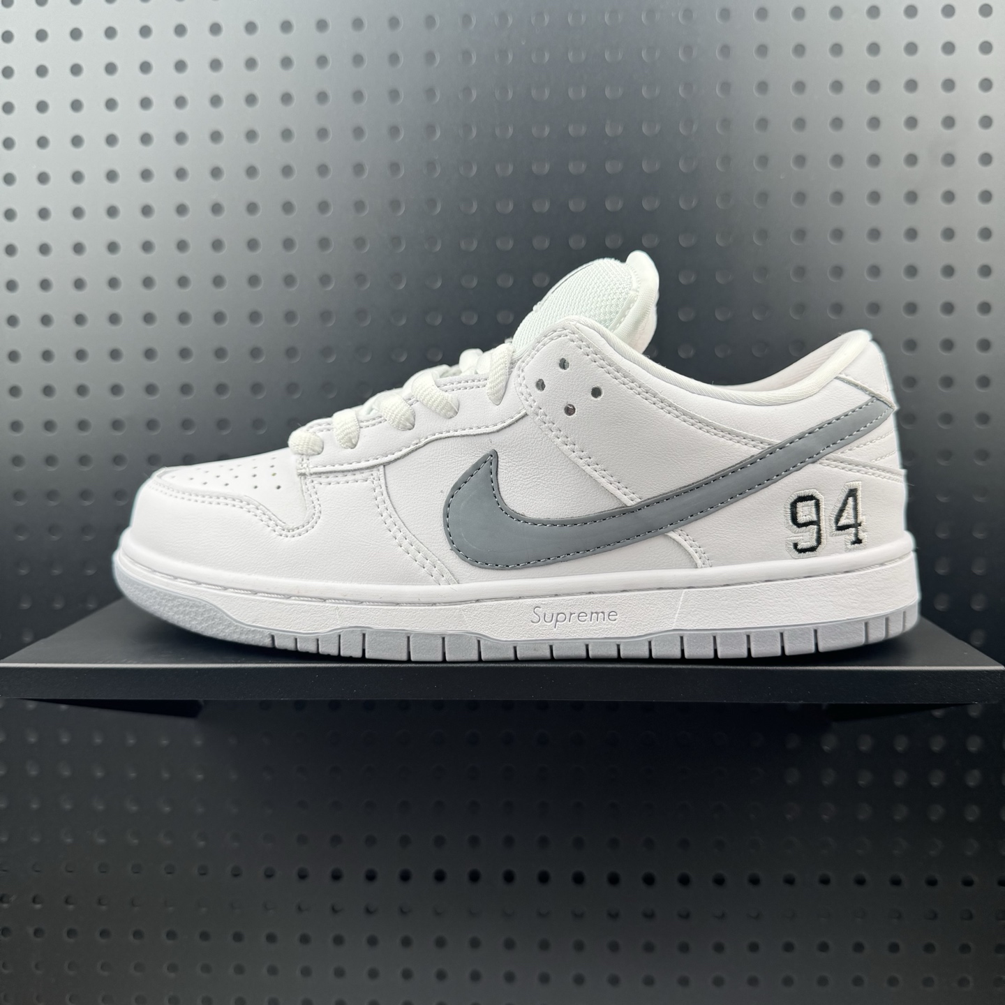Supreme x Nike Dunk SB Low 白色 此款鞋跟上绣有“94”字样,纪念品牌的创立年份,该品牌的标志性徽标还被蚀刻在了中底的侧壁上.鞋垫沿用了标准的白色表面,每只鞋垫上都有Nike SB标识,并且Supreme的标识横跨左右两只鞋垫. 货号: HQ8487-100 (24)