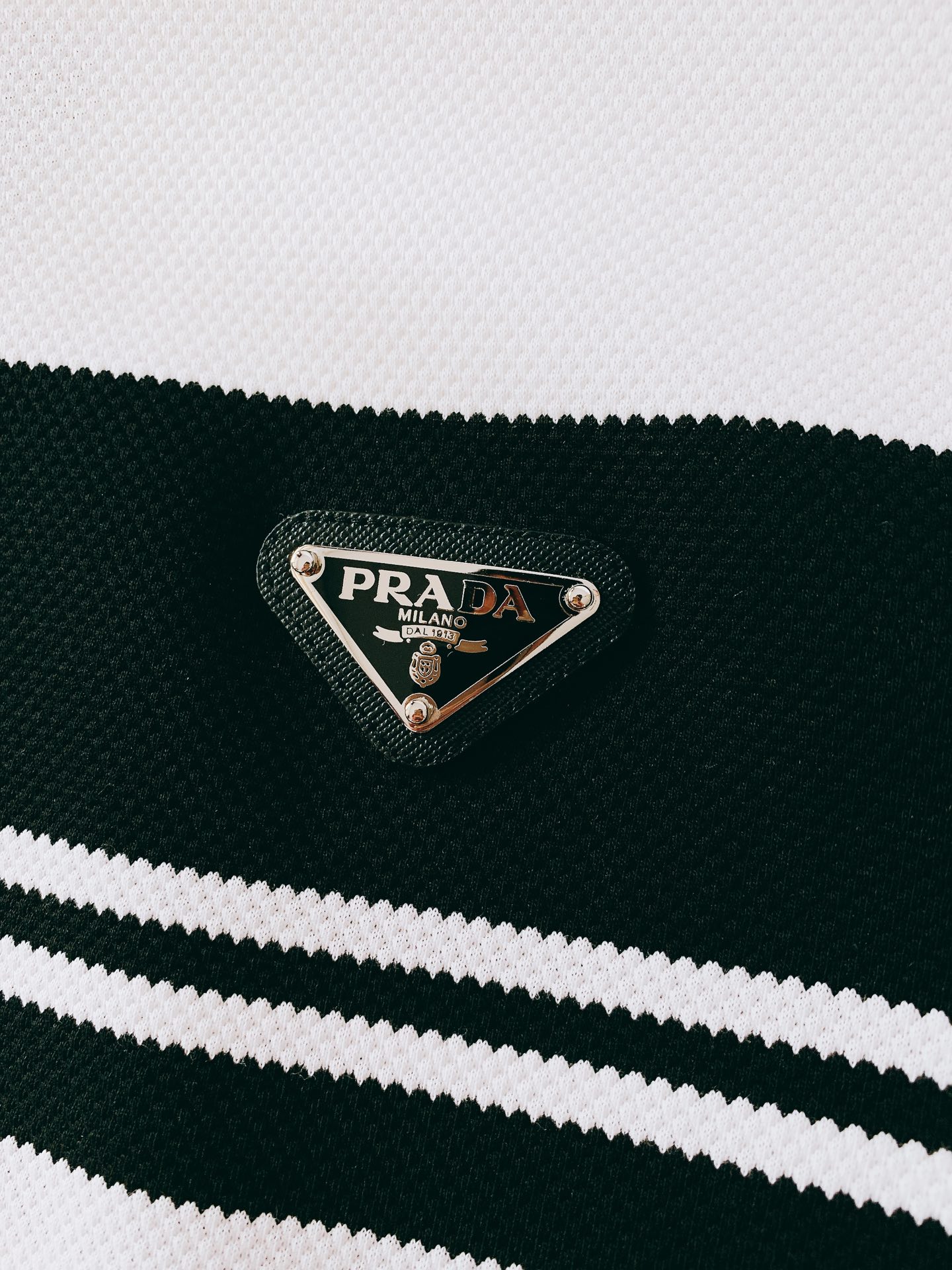 
Prada 普拉达 2025SS春夏新品 
撞色翻领T恤，甄选优质透气面料。胸前经典三角标五金装饰搭配