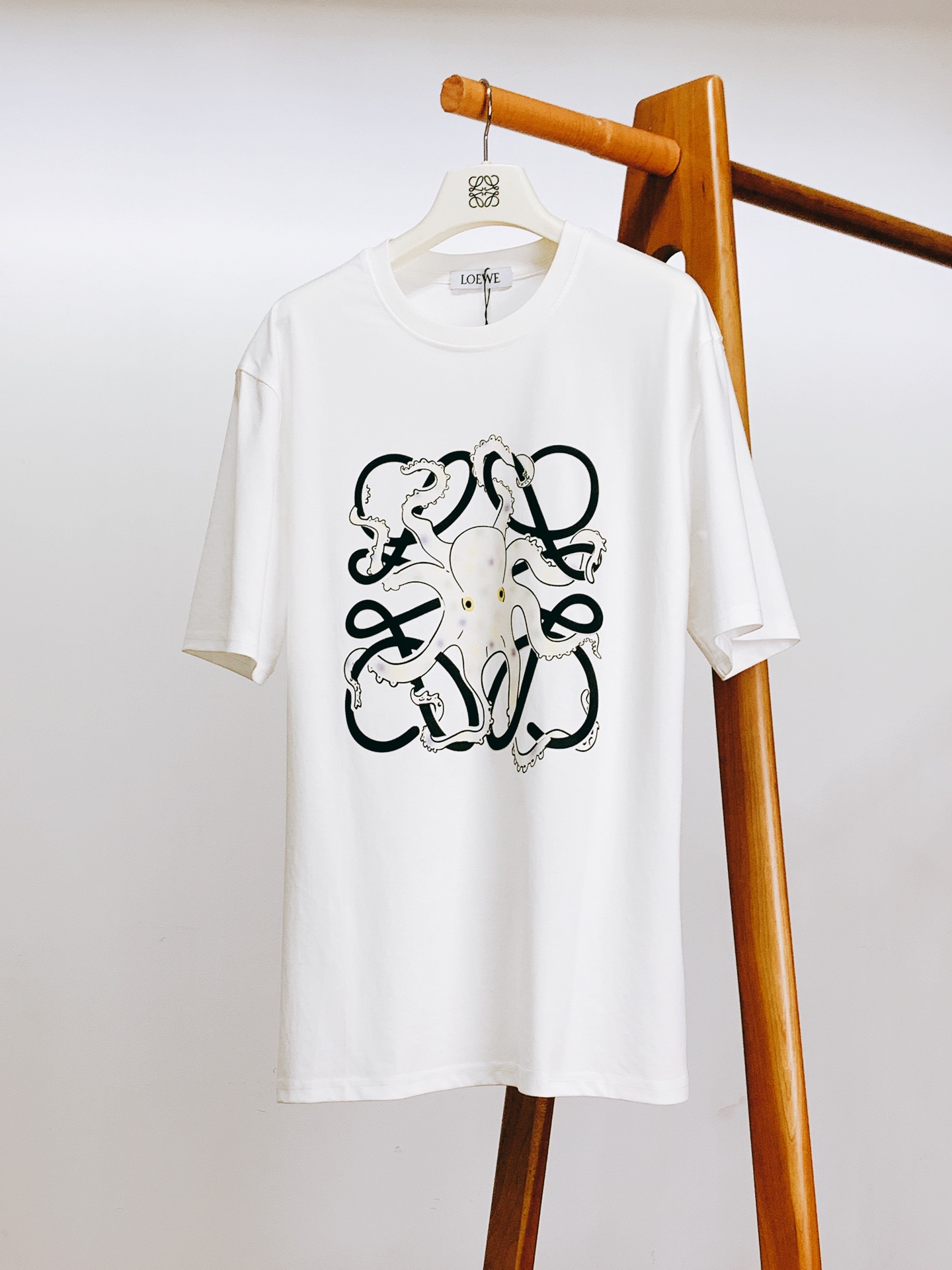 NO:459034,Loewe 2025SS Spring and Summer New Product Creative Octopus Logo T-shirt. The octopus printed pattern on the chest is the visual focus. The main body of the octopus is pure white, dotted with yellow and purple spots, which is lively and playful. Its eyes are bright and eye-catching, as if it contains a mysterious ocean atmosphere. The tentacles of the octopus are stretched freely, with rich details on the edges, and the portrayal of the suction cup is lifelike, adding to the realism and three-dimensionality of the pattern. Behind the octopus pattern, the brand's iconic elements are cleverly incorporated, presented in dark colors, and contrasting with the octopus pattern, which not only highlights the brand's characteristics, but also adds the layering of the pattern, as if the octopus is swimming in the ocean of intertwined brand elements, showing the brand's unique artistic aesthetic to the fullest, and the upper body instantly makes the outfit full of personality and artistic style. ………………………………………………………………………………………………………………………………………………………………………………………………………………………………………………………………………………………………………………………………………………………………………………………………………………………………………………………………………………………………………………………………………………………………………………………………………………………………………………………………………………………………  SizeM-3XL, loewe,loewe,tees,t-shirt,alexander wang19860909Loewe 罗意威 2025SS春夏新品 创意章鱼标识T恤.胸前的章鱼印花图案是视觉焦点.章鱼主体呈纯净白色,点缀着黄紫相间的斑点,灵动又俏皮.它的眼睛明亮醒目,仿佛蕴含着神秘的海洋气息.章鱼的触须肆意伸展,边缘细节丰富,吸盘的刻画栩栩如生,增加了图案的真实感与立体感. 在章鱼图案背后,巧妙融入了品牌标志性元素,以深色呈现,与章鱼图案相互映衬,既凸显了品牌特色,又增添了图案的层次感,仿佛章鱼在品牌元素交织的海洋中畅游,把品牌独特的艺术审美展现得淋漓尽致,上身瞬间让穿搭充满个性与艺术格调. …………………………………………………… SizeM-3XL,,loewe,loewe,tees，t-shirt,alexander wang,Men's clothing