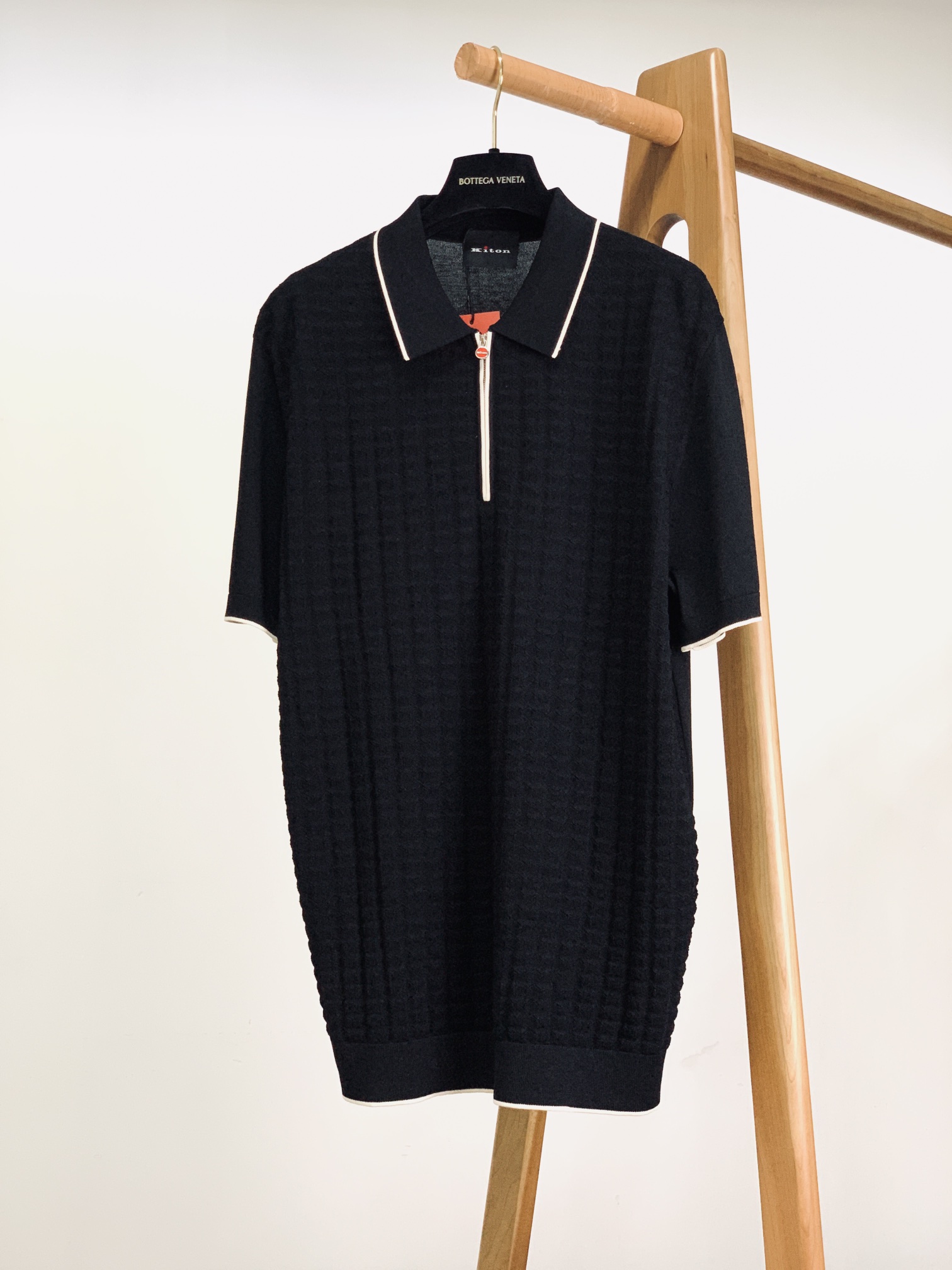 Elegante polo negro Bottega Veneta con cremallera y patrón texturizado