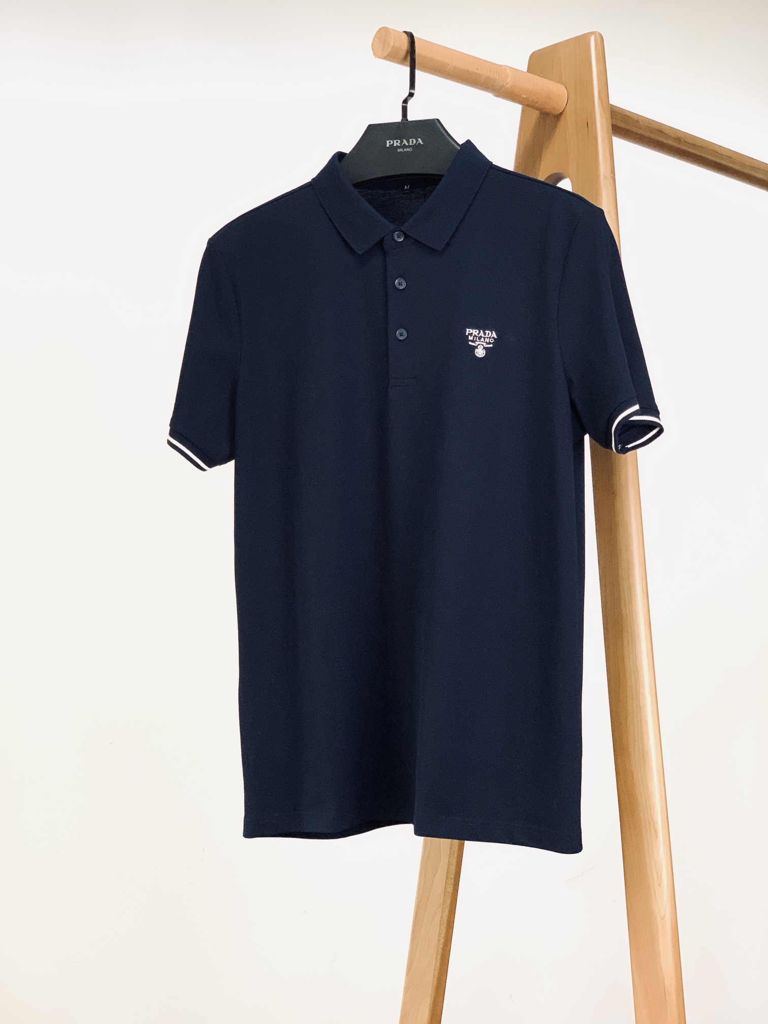 NO:432297,Prada 2025SS Spring and Summer New Product Classic Reshaping, Casual Lapel T-shirt, Details are true. The neat lapel design inherits the elegant genes of the Polo shirt, fits the neck lines, and the business sense and leisure feel are balanced and blended in every move. The three buttons of the cloak are carefully selected, and the texture is matte finish is harmoniously echoing the tone of the body, and the buttons are smooth, and the details show quality control. The front and back embroidered logo is presented with exquisite craftsmanship, with fine and regular stitching and full of three-dimensionality. Break the monotony of the solid color and inject design ingenuity into the simple body. When walking, details appear with the steps, adding a sense of layering of the dressing.  Selected high-quality beaded floor fabrics, which feel soft and skin-friendly, and have good breathability and clarity. They are comfortable and can maintain a neat style when worn every day. They are accurate in cutting, fit ergonomics, natural and smooth in shoulder lines, and have a good drape. Whether you wear them alone, they can adapt to diverse scenes, allowing you to interpret fashion taste with exquisite details on different occasions. ……………………………………………………………………………………………………………………………………………………………………………………………………………………………………………………………………………………………………………………………………………………………………………………………………………………………………………………………………………………………………………………………………………………………………………………………………………………………………………………………………………………………………………………………………………………………………………………………………………………………………………………………………………………………………………………………………………………………………………………………………………………………………………………………………………………………………………………………19860909Prada 普拉达 2025SS春夏新品 经典重塑,休闲翻领 T 恤,细节见真章 利落翻领设计,承袭 Polo 衫的优雅基因,贴合颈部线条,举手投足间,商务感与休闲感平衡交融.门襟三颗纽扣,选料讲究,质感哑光饰面,与衣身色调和谐呼应,扣合顺滑,细节处彰显品质把控 . 前后密针刺绣标识,以精湛工艺呈现,线迹细密规整,立体感十足.打破纯色单调,为简约衣身注入设计巧思,行走间,细节随步伐若隐若现,增添穿搭层次感 . 精选优质珠地面料,触感柔软亲肤,兼具良好透气性与挺括度,日常穿着,自在舒适又能保持利落版型.剪裁精准,贴合人体工学,肩部线条自然流畅,衣身垂坠感佳,无论单穿彰显随性,还是内搭营造层次,都能适配多元场景,让你在不同场合,都以精致细节,诠释时尚品味 . …………………………………………………… SizeM-3XL,,prada,prada,alexander wang,Men's clothing