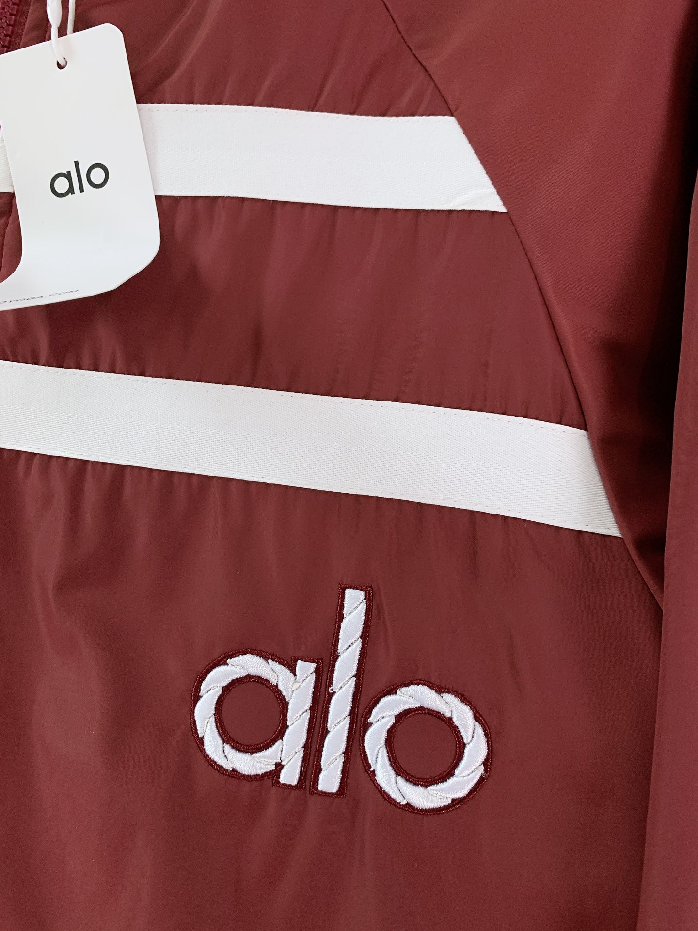 ALO 阿洛 2025FW早秋新品 连帽运动外套。它以轻量防风的面料打造利落廓形，连帽设计可随天气与造型