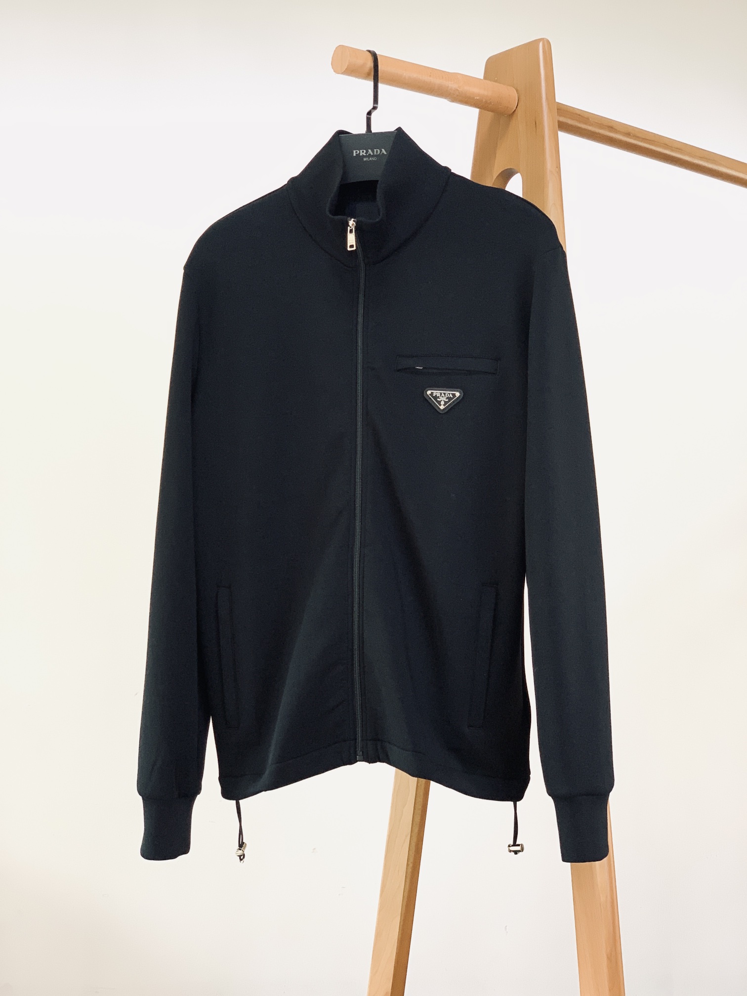 NO:595167,Prada's 2025FW early autumn new product, the triangle logo air layer zipper jacket has a minimalist black tone with a sense of functionality and luxury. It is made of high-density air layer fabric, the outer layer is stiff and anti-wrinkle, and the inner layer is soft and elastic and skin-friendly - it does not have the bloated feeling of heavy fabrics, but can also lock in the moderate warmth of autumn and winter. It is breathable and not stuffy. It is a lightweight jacket that can be worn alone or layered.  The chest zipper pocket is embedded with the classic triangle logo and is fixed with metal rivets, turning the brand logo into a 'functional decoration', low-key but self-recognizable; the main zipper puller is engraved with the brand letter logo, and the zipper pulls smoothly without any lag. Even the pocket zippers continue to have the same texture of hardware, which is exquisite from the inside to the outside;  The drawstring at the hem is matched with a brand-embossed metal buckle, allowing you to freely adjust the tightness of the silhouette - loosen it for a relaxed and lazy look, tighten it for a sharp waistline, suitable for different wearing scenarios. The slightly loose shoulder design is compatible with various body shapes. Paired with white T-denim, it is a street functional style, while paired with a turtleneck sweater and trousers, it is a sophisticated and luxurious look. One piece can be used for multiple styles in autumn and winter. Size S, length 65, bust 104, shoulder width 43.5, sleeve length 65  Size M, length 67, bust 108, shoulder width 45, sleeve length 66, size L, length 69, bust 112, shoulder width 46.5, sleeve length 67, size XL, length 71, bust 116, shoulder width 48, sleeve length 68.19860909Prada 普拉达 2025FW早秋新品 三角徽标空气层拉链夹克极简黑调里的机能奢感 采用高密度空气层面料,外层挺括抗皱,内层软弹亲肤——既没有厚重面料的臃肿感,又能锁住秋冬的适度暖意,透气不闷汗,是“单穿/叠穿都适配”的轻量外套. 胸前拉链口袋嵌入经典三角徽标,金属铆钉固定的设计,把品牌标识做成“机能装饰”,低调却自带辨识度； 主拉链头刻有品牌字母标识,拉合顺滑无卡顿,连口袋拉链都延续同质感五金,从内到外的精致； 下摆抽绳搭配品牌压纹金属扣,自由调节廓形松紧——松开是松弛慵懒,收紧则显利落腰线,适配不同穿搭场景. 微宽松落肩版型,兼容各种身形,搭白T牛仔是街头机能风,配高领毛衣+西裤则是轻熟奢感,一件就能贯穿秋冬的多风格造型. S码衣长65 胸围104 肩宽43.5 袖长65 M码衣长67 胸围108 肩宽45 袖长66 L码衣长69 胸围112 肩宽46.5 袖长67 XL码衣长71 胸围116 肩宽48 袖长68 …………………………………………………… SizeS-XL,,prada,prada,jackets & coats,jackets & coats,sweaters,alexander wang,Men's clothing