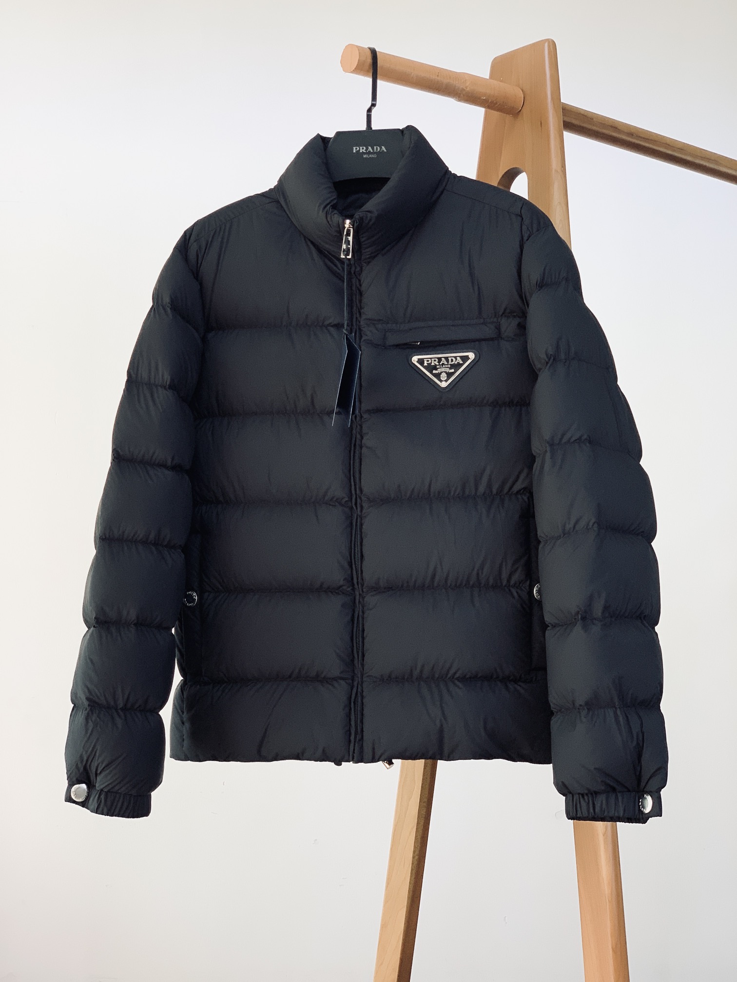 NO:595148,Prada's 2025FW new autumn and winter products combine the minimalist aesthetics of fashionable and casual down jackets with luxurious warmth. The iconic triangle logo is embedded in the body with a metallic texture. It is low-key and self-recognizable, and is the finishing touch of the minimalist style. The zippers and snap buttons are engraved with the brand's letter logo, and the drawstring hardware from the collar to the cuffs hides the luxury quality of 'not noisy, but has its own sound' everywhere;  The stand-up collar + waist-cinching drawstring style can not only wrap the neck and shoulders to resist cold wind, but also adjust the outline through the drawstring, making it suitable for commuting, leisure and other scenarios. The interior is filled with No. 90 high-loft down, which is full of down and strong resilience. It can quickly store heat when wrapped lightly around the upper body, saying goodbye to the bloated and bulky style of traditional down jackets, allowing the winter style to maintain neat lines; the wind resistance of Re-Nylon fabric adds a layer of 'invisible protection' to warmth.  The classic two-tone color of black and white is the 'hard currency' that will never go wrong in the wardrobe - black is low-key, suitable for the calm aura in the workplace; white is clean and clear, unlocking the relaxed atmosphere of winter wear. Size 48 bust 112 sleeve length 63 dress length 68 shoulder width 47 size 50 bust 116 sleeve length 64 dress length 69 shoulder width 48 size 52 bust 120 sleeve length 65 dress length 70 shoulder width 49  Size 54 Bust 124 Sleeve Length 66 Clothes Length 71 Shoulder Width 50 Size 56 Bust 128 Sleeve Length 67 Clothes Length 72 Shoulder Width 51 ……………………………………………………………… Size48-56,,prada,prada,down jacket,alexander wang19860909Prada 普拉达 2025FW秋冬新品 时尚休闲羽绒服极简美学与奢级保暖的双向奔赴 标志性三角徽标以金属质感嵌入衣身,低调中自带辨识度,是极简造型的点睛之笔； 拉链、按扣均刻印品牌字母标识,从领口到袖口的抽绳五金,每一处都藏着“不喧哗,自有声”的奢品质感； 立领+收腰抽绳的版型,既能包裹颈肩抵御寒风,又能通过抽绳调整轮廓,适配通勤、休闲等多场景穿搭. 内里填充90号高蓬松羽绒,绒朵饱满、回弹性强,轻裹上身即能快速蓄热,告别传统羽绒服的臃肿笨重,让冬日造型保持利落线条；Re-Nylon面料的抗风性,更让温暖多了一层“隐形防护”. 黑与白的经典双色,是衣柜里永不出错的“硬通货”——黑色低调藏肉,适配职场的沉稳气场；白色干净清透,解锁冬日穿搭的松弛氛围感. 48码胸围112袖长63衣长68肩宽47 50码胸围116袖长64衣长69肩宽48 52码胸围120袖长65衣长70肩宽49 54码胸围124袖长66衣长71肩宽50 56码胸围128袖长67衣长72肩宽51 …………………………………………………… Size48-56,,prada,prada,down jacket,alexander wang,Men's clothing