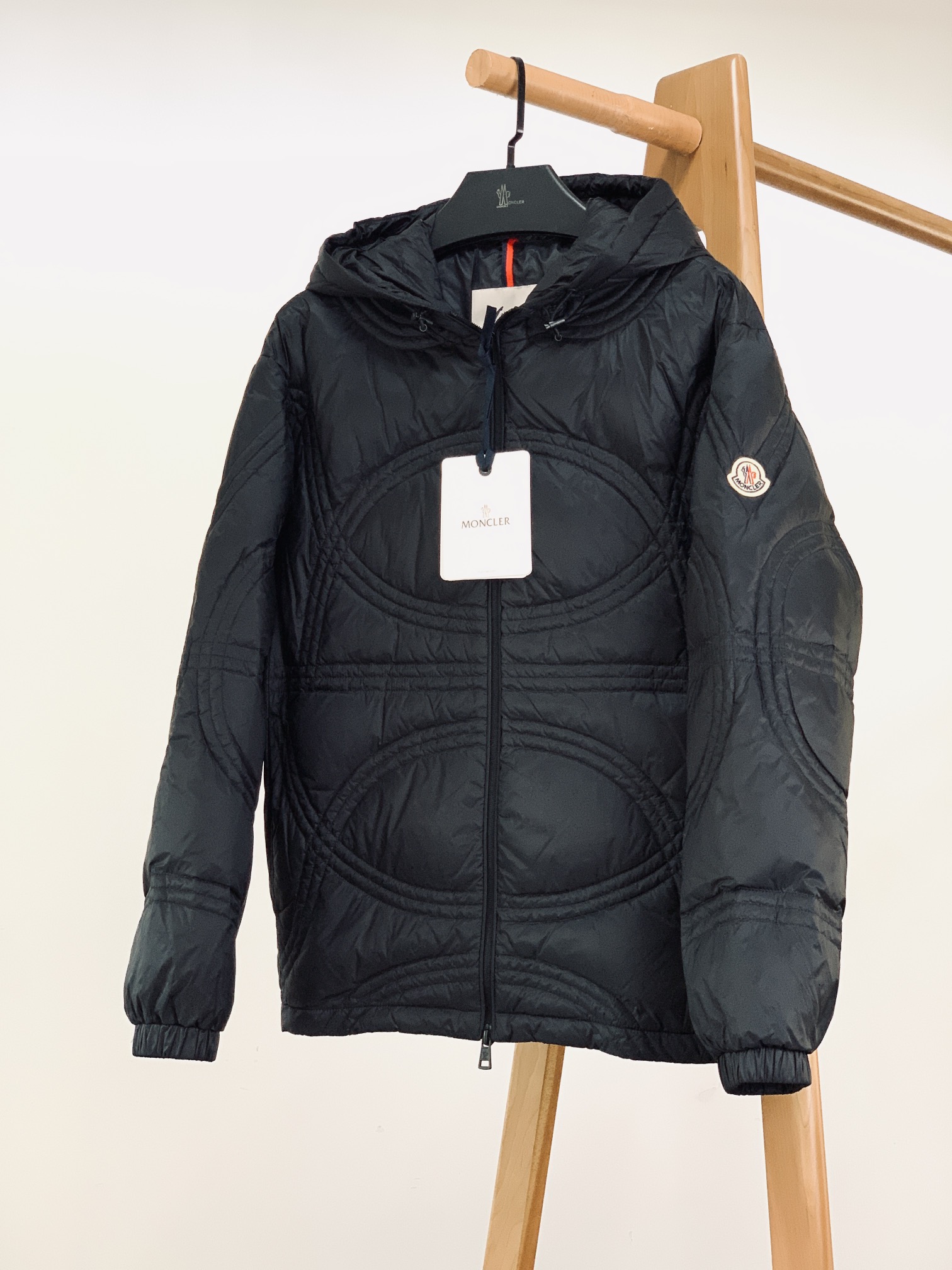 NO:595139,Moncler's 2025FW autumn and winter new product is the geometric quilted hooded down jacket. It has a high fill power of 90 down, which can quickly store heat when wrapped lightly around the upper body, and can maintain stretch and warmth even in a -15℃ environment, saying goodbye to the bulk and bulkiness of traditional down jackets; the body adopts three-dimensional circular quilting, breaking the monotony of conventional horizontal strips of down filling, and the lines flow with the shape when walking, so that thermal clothing can also be worn with a 'fashionable sense';  The hooded design wraps up the cold wind on the neck and shoulders, and the drawstring at the hem can freely adjust the silhouette, adapting to the neatness of commuting or the relaxation of leisure. The embroidered logo badge on the sleeves is a low-key identity mark, with a sense of luxury that is 'not noisy but substantial'; the zipper and drawstring buckle are engraved with the brand logo, and every small detail from the collar to the cuffs hides the sophistication of 'luxury grade';  The dark black matte fabric has a low-key luster, is wind-resistant and waterproof, and makes the outfit more stable and high-end. One piece can revitalize the entire winter wardrobe. ……………………………………………… Size 1-5, Moncler, down jacket, hats, alexander wang19860909Moncler 蒙口 2025FW秋冬新品 几何绗缝连帽羽绒服.高蓬松度90绒填充,轻裹上身即能快速蓄热,-15℃环境也能保持舒展暖意,告别传统羽绒服的臃肿笨重； 衣身采用立体环形绗缝,打破常规横条充绒的单调,走动间线条随身形流动,让保暖装也能穿出“时装感”； 连帽设计包裹颈肩寒风,下摆抽绳可自由调节轮廓,适配通勤的利落与休闲的松弛. 袖身的标识刺绣徽章,是低调的身份标识,自带“不喧哗而有分量”的高级感； 拉链、抽绳扣均刻印品牌标识,从领口到袖口的每处小细节,都藏着“奢品级”的考究； 深黑色哑光面料自带低调光泽,抗风防水的同时,让穿搭更显沉稳高级.一件盘活整个冬季衣橱. …………………………………………………… Size1-5码,,Moncler,down jacket,hats,alexander wang,Men's clothing