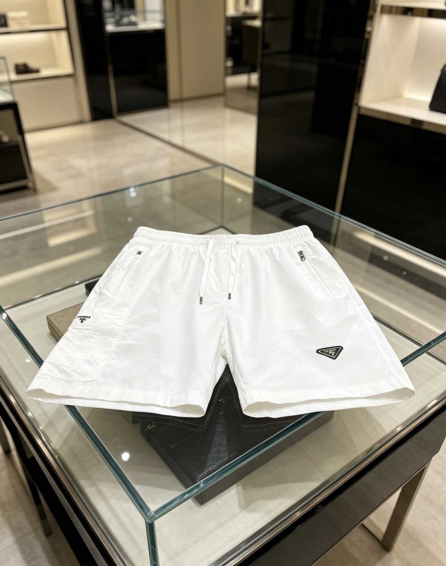 NO:847490,Prada Prada  2026ss summer classic triangle logo functional shorts, reconstructing summer casual aesthetics with minimalist lines. High-density anti-wrinkle nylon fabric is selected, which is smooth to the touch and has excellent breathability. It is light and burdenless to wear in summer; the elastic drawstring design at the waist is suitable for various body shapes and can be matched with  Equipped with double zipper side pockets and three-dimensional work patch pockets, the storage is full of security. The iconic enamel triangle logo on the front is the finishing touch, the webbing logo on the back has rigorous details, and the neat straight silhouette modifies the leg shape. Whether you are commuting in the city or traveling outdoors, you can easily create a high-end sense of relaxation.  Color Black White Size 48-56, prada, prada, shorts,19860909Prada 普拉达 2026ss夏季经典三角标机能短裤,以极简线条重构夏日休闲美学.甄选高密抗皱锦纶面料,触感顺滑且具备极佳透气性,夏日穿着轻盈无负担；腰头弹力抽绳设计适配各种身形,搭配双拉链侧袋与立体工装贴袋,收纳安全感拉满.正面标志性珐琅三角徽标点睛,背面织带标细节严谨,利落直筒版型修饰腿型,无论是都市通勤还是户外出行,皆能轻松演绎高阶松弛感. 颜色黑色 白色 码数48-56,,prada,prada,shorts,,Men's clothing