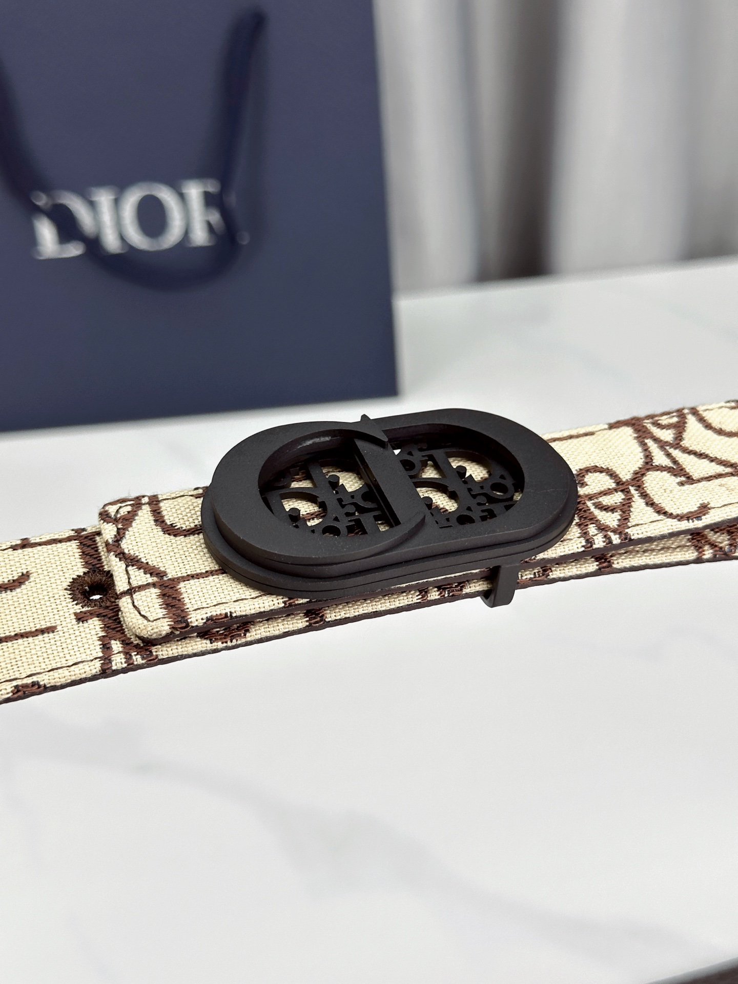 宽度3.5cm 这款腰带扣以 Oblique Cosmo 图案金属饰牌诠释品牌经典图案，以金色/白色饰面