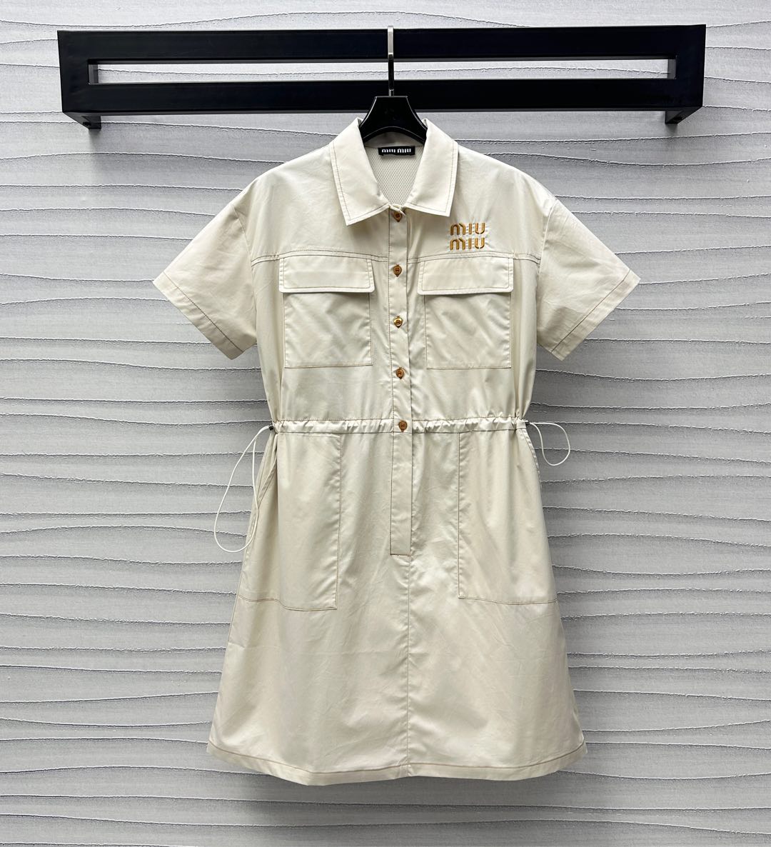 NO:332955,Miumi*2025 new product, custom-made drawstring work dress, YB imported twill cotton, crisp, comfortable and stylish, half-pallet button adjustment design, combined with symmetrical flip pocket decoration on the chest, add layered look, straight-tube style with drawstring on both sides outlines the waist, loosen and tied to two pieces, to cover the flesh and inclusive effect, embroidered with the iconic letter embroidery logo on the chest, highlighting the brand tone, surface auxiliary material development, lapel short-sleeved dress tailoring, the upper body is full of literary and elegant atmosphere, and it is easy to wear on daily commuting and vacation to create a fashionable and relaxed feeling. High-end version,,miumiu, skirts, T-shirt, alexander wang19860909Miumi*2025新品上架抽绳工装连衣裙定制YB进口斜纹全棉材质 挺括舒适有型 沿用半开襟纽扣调节设计 配合胸前对称翻盖口袋装饰 增添造型层次感 直筒版型搭配两侧抽绳勾勒腰身可松可系两穿 起到遮肉包容效果 胸前点缀标志性字母刺绣徽标 彰显品牌调性 面辅料开发 翻领短袖连衣裙剪裁 上身充满文艺优雅气息 日常通勤度假轻松穿搭出时髦松弛感  高版本,,miumiu,skirts,T-shirt,alexander wang,Women's clothing