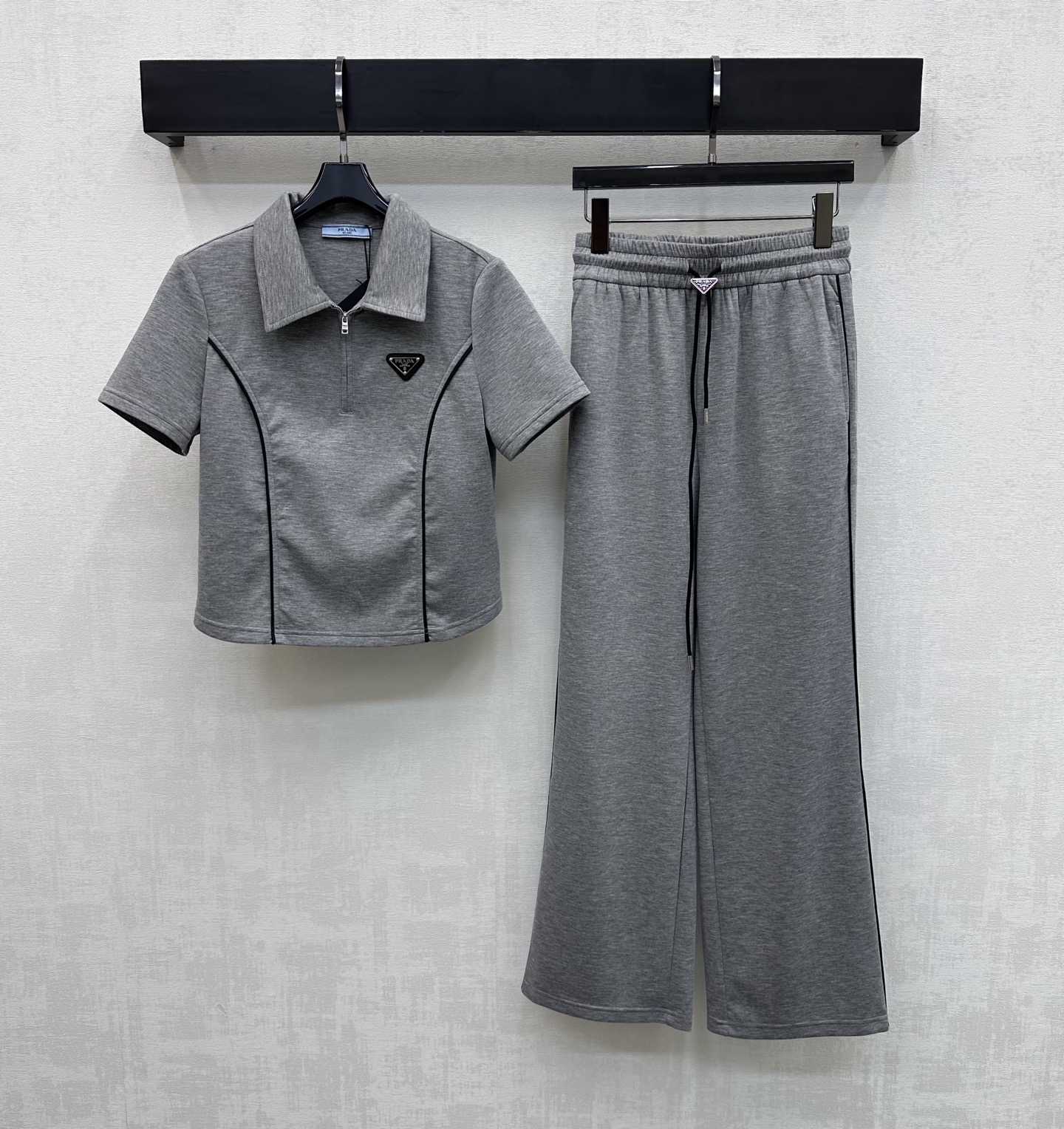 NO:750224,Prad*2026 new arrival lapel slim suit. Customized YB imported cotton material. The texture is fine and comfortable. The top half-open zipper adjustment is combined with the contrasting outline binding design to create a visual slimming effect. Add a sense of layering to the look. The iconic metal triangle logo embellishment highlights the brand tone. Surface accessories development. The lapel short-sleeved top is cut with drawstring straight trousers. The details echo up and down. The complete set is simple and fashionable. High version 2 colors, prada, T-shirt,19860909Prad*2026新品上架翻领修身套装 定制YB进口棉纶材质 质感细腻舒适 上衣半开襟拉链调节配合撞色轮廓捆边设计 打造视觉显瘦效果 增添造型层次感 标志性金属三角徽标点缀装饰 彰显品牌调性 面辅料开发 翻领短袖上衣抽绳直筒长裤剪裁 细节上下呼应 成套穿搭简约不失时尚感   高版本2色,,prada,T-shirt,,Women's clothing