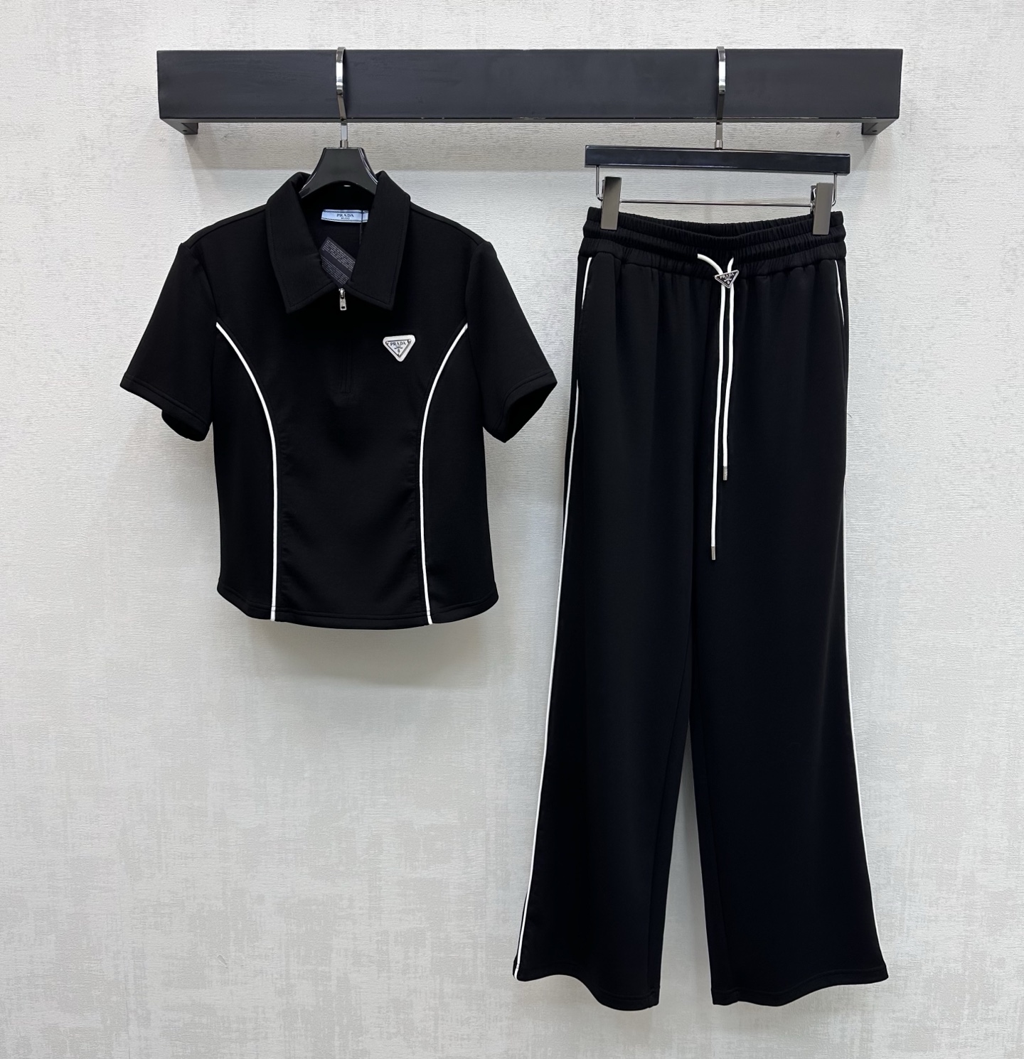 NO:750190,Prad*2026 new arrival lapel slim suit. Customized YB imported cotton material. The texture is fine and comfortable. The top half-open zipper adjustment is combined with the contrasting outline binding design to create a visual slimming effect. Add a sense of layering to the look. The iconic metal triangle logo embellishment highlights the brand tone. Surface accessories development. The lapel short-sleeved top is cut with drawstring straight trousers. The details echo up and down. The complete set is simple and fashionable. High version 2 colors, prada, T-shirt,19860909Prad*2026新品上架翻领修身套装 定制YB进口棉纶材质 质感细腻舒适 上衣半开襟拉链调节配合撞色轮廓捆边设计 打造视觉显瘦效果 增添造型层次感 标志性金属三角徽标点缀装饰 彰显品牌调性 面辅料开发 翻领短袖上衣抽绳直筒长裤剪裁 细节上下呼应 成套穿搭简约不失时尚感   高版本2色,,prada,T-shirt,,Women's clothing