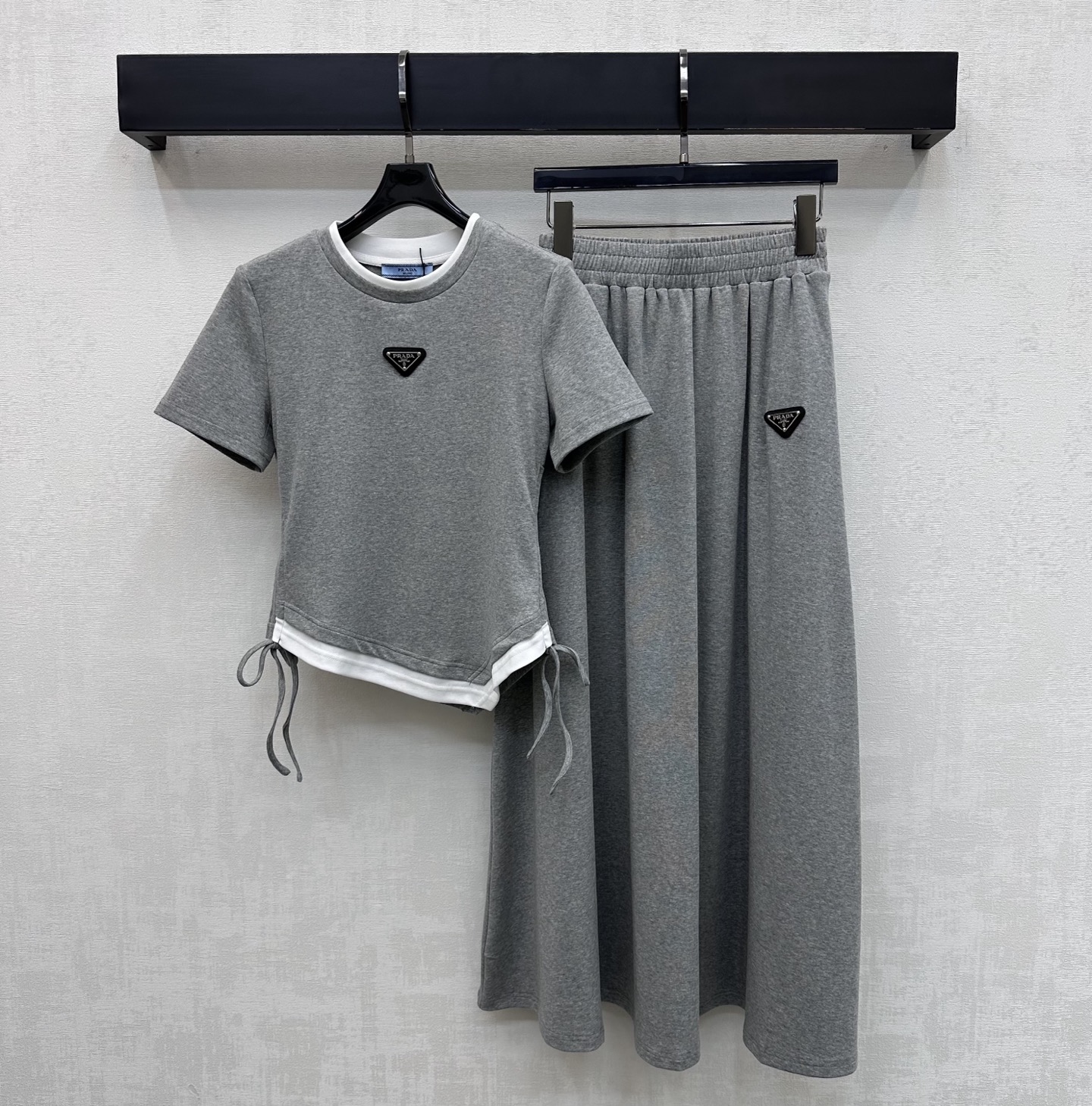 NO:752273,Prad*2026 new arrivals, fake two-piece T-shirt and skirt suit, customized with YB imported twill cotton material, high quality, comfortable and breathable. The collar and hem are processed with fake two-piece contrasting details. It is matched with a symmetrical drawstring adjustment design to add layering to the look. The chest is embellished with the iconic triangle logo decoration, echoing elements from top to bottom to highlight the brand tone. Development of surface accessories. Slim-fitting short T-shirt, pleated long skirt cut. Simple and relaxed daily commuting wear.  High version 3 colors, prada, skirts, tees, t-shirt,19860909Prad*2026新品上架假两件T恤半裙套装定制YB进口斜纹棉材质 质感上乘 舒适透气 领口衣摆采用拼接撞色假两件细节处理 配合对称抽绳调节设计 增添造型层次感 胸前点缀标志性三角徽标装饰 上下呼应元素 彰显品牌调性 面辅料开发 修身短款T恤压褶长半裙剪裁 日常通勤穿搭简约松弛  高版本3色,,prada,skirts,tees，t-shirt,,Women's clothing