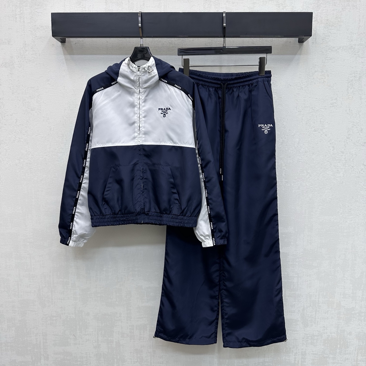 NO:752692,Prad*2025 new products are on the shelves, contrasting color hooded jacket and trousers suit, customized with YB imported nylon material, crisp and stylish, full of texture. Ready-to-wear garments follow the layered contrasting splicing design, and are outlined with letter webbing to form a raglan effect and add layering to the look. The cuffs and hems are elastic and the hem drawstring adjusts to fit the body, making it lighter and more flexible. The chest is embellished with iconic letter embroidery logo decoration, which echoes the details of the trousers up and down, highlighting the brand tone. Development of surface accessories  Hooded jacket and drawstring straight trousers are cut with first-class windproof effect to enhance the fashion of outdoor activities. High version, prada,jackets & coats,jackets & coats,hats,19860909Prad*2025新品上架撞色连帽外套长裤套装定制YB进口尼龙材质 挺括有型 质感十足 成衣沿用层次撞色拼接设计 配合字母织带捆边勾勒 形成插肩轮廓效果 增添造型层次感 袖口下摆松紧搭配衣摆抽绳调节贴合身型 更轻便灵活 胸前点缀标志性字母刺绣徽标装饰 与裤子细节上下呼应 彰显品牌调性 面辅料开发 连帽夹克外套抽绳直筒长裤剪裁 防风效果一流 提升户外活动穿搭的时尚度  高版本,,prada,jackets & coats,jackets & coats,hats,,Women's clothing