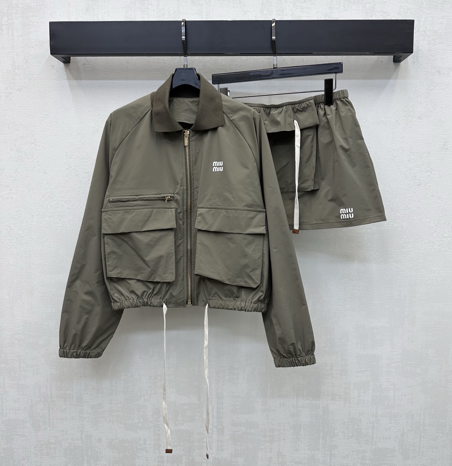 NO:799117,Miumi*2026 new arrivals hooded drawstring work suit, custom made of YB imported recycled nylon material, stiff, comfortable and stylish, zipper placket adjustment on the front of the chest and contrasting color treatment of the drawstring on the hem, matched with symmetrical workwear flap pocket design, adding layering to the look, presenting a casual and fashionable sense of work wear, emblazoned with the iconic letter logo on the chest to highlight the brand's tone, development of surface accessories, lapel zipper jacket, drawstring skirt cut, details echoed from top to bottom  Complete set of upper body, fashionable and suitable for daily commuting, high version 2 colors,,miumiu,skirts,jackets & coats,jackets & coats,hats,19860909Miumi*2026新品上架连帽抽绳工装套装定制YB进口再生尼龙材质 挺括舒适有型 胸前沿用拉链开襟调节与下摆抽绳撞色处理 配合对称工装翻盖口袋设计 增添造型层次感 呈现工装休闲时尚感 胸口点缀标志性字母徽标装饰 彰显品牌调性 面辅料开发 翻领拉链夹克外套抽绳半裙剪裁 细节上下呼应 成套上身日常通勤时髦洋气适配穿搭 高版本2色,,miumiu,skirts,jackets & coats,jackets & coats,hats,,Women's clothing