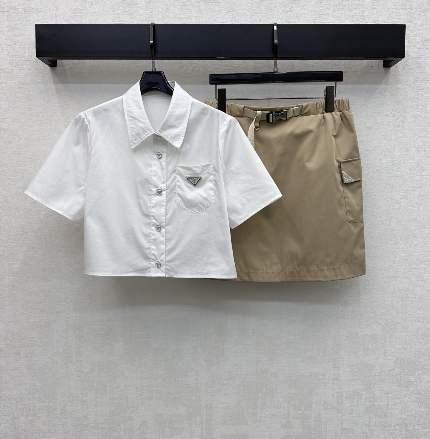 NO:808752,Prad*2026 new arrival short-sleeved shirt and skirt suit customized YB imported twill cotton nylon material, breathable, comfortable and full of texture. Regular lapel version with placket button adjustment design to add layering to the look. The iconic metal triangle logo decoration on the chest echoes the upper and lower detail design to highlight the brand tone. Development of surface accessories. Lapel short-sleeved shirt with buckle webbing skirt cut. Daily commuting complete set with high fashion.  High version 2 colors, prada,skirts,T-shirt,19860909Prad*2026新品上架短袖衬衣半裙套装定制YB进口斜纹全棉尼龙材质 透气舒适 质感十足 常规翻领版型配合开襟纽扣调节设计 增添造型层次感 胸口点缀标志性金属三角徽标装饰 呼应上下细节设计 彰显品牌调性 面辅料开发 翻领短袖衬衣卡扣织带半裙剪裁 日常通勤成套穿搭高级时髦  高版本2色,,prada,skirts,T-shirt,,Women's clothing