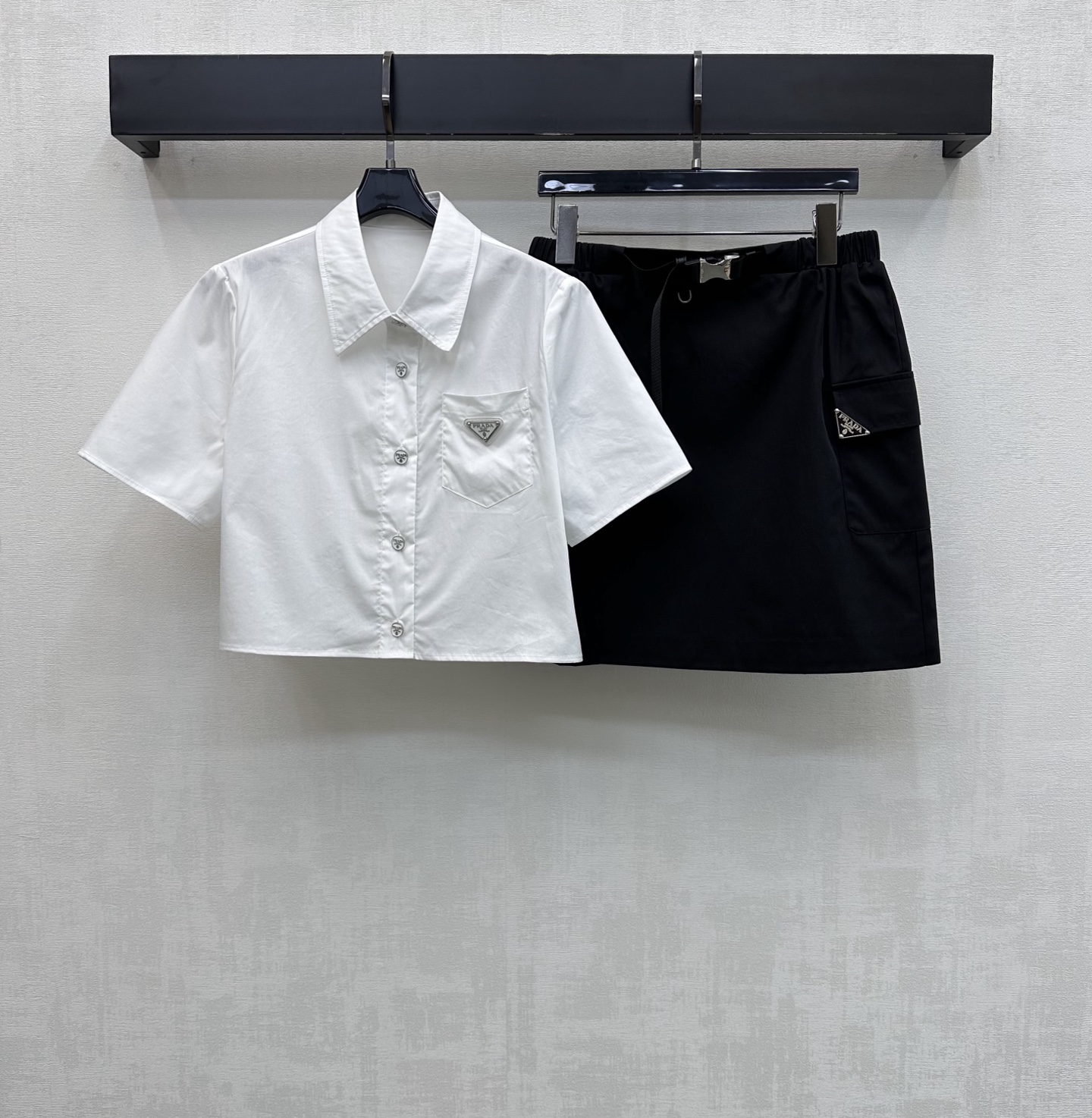 NO:808748,Prad*2026 new arrival short-sleeved shirt and skirt suit customized YB imported twill cotton nylon material, breathable, comfortable and full of texture. Regular lapel version with placket button adjustment design to add layering to the look. The iconic metal triangle logo decoration on the chest echoes the upper and lower detail design to highlight the brand tone. Development of surface accessories. Lapel short-sleeved shirt with buckle webbing skirt cut. Daily commuting complete set with high fashion.  High version 2 colors, prada,skirts,T-shirt,19860909Prad*2026新品上架短袖衬衣半裙套装定制YB进口斜纹全棉尼龙材质 透气舒适 质感十足 常规翻领版型配合开襟纽扣调节设计 增添造型层次感 胸口点缀标志性金属三角徽标装饰 呼应上下细节设计 彰显品牌调性 面辅料开发 翻领短袖衬衣卡扣织带半裙剪裁 日常通勤成套穿搭高级时髦  高版本2色,,prada,skirts,T-shirt,,Women's clothing