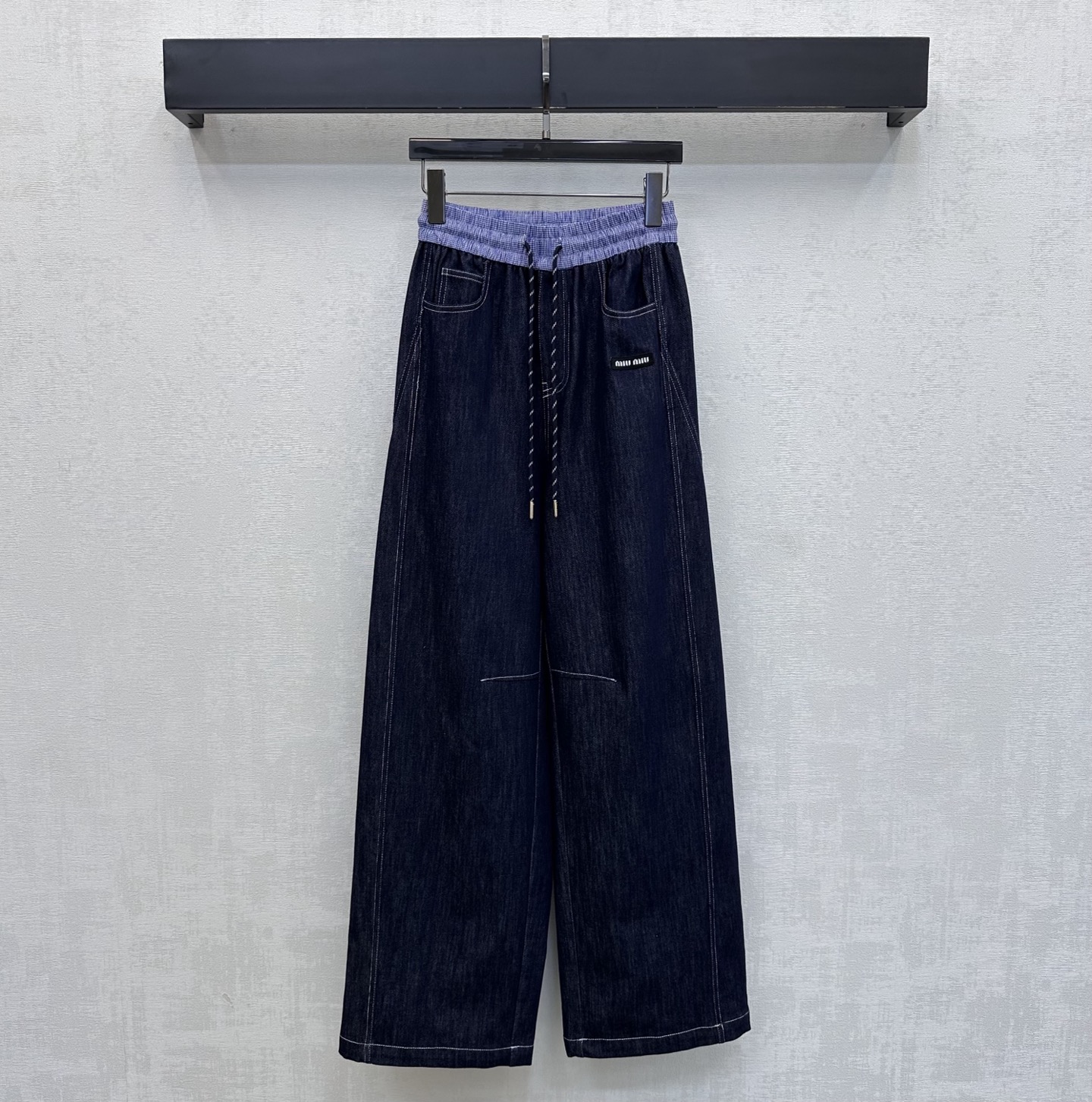 NO:831571,Miumi*2026 new products are on the shelves. The spliced scimitar denim trousers are made of YB imported twill cotton denim denim. They are very wide, comfortable and stylish. The whole body is washed with dark primary colors to create a retro texture. The side pockets are decorated with iconic letter logos to highlight the brand tone. The contrasting color design of the waistband of plaid shirt fabric is used. The dividing line is sewn at the knee bend to create a scimitar effect. Effectively modify the straight leg line to wear without a sense of restraint. Add a sense of layering to the look. Development of surface accessories  High-waisted drawstring wide-leg trousers, casual and fashionable for daily commuting, high version,,miumiu,19860909Miumi*2026新品上架 拼接弯刀牛仔长裤定制YB进口斜纹棉丹宁牛仔材质 挺阔舒适有型 通体采用深色原色水洗工艺处理 打造复古质感 侧口袋点缀标志性字母徽标装饰 彰显品牌调性 沿用格纹衬衣面料腰头拼接撞色设计 配合膝弯处缝制分割线打造弯刀效果 有效修饰直腿线条穿着无束缚感 增添造型层次感 面辅料开发 高腰抽绳阔腿长裤剪裁 日常通勤随意搭配穿搭时髦高级 高版本,,miumiu,,Women's clothing