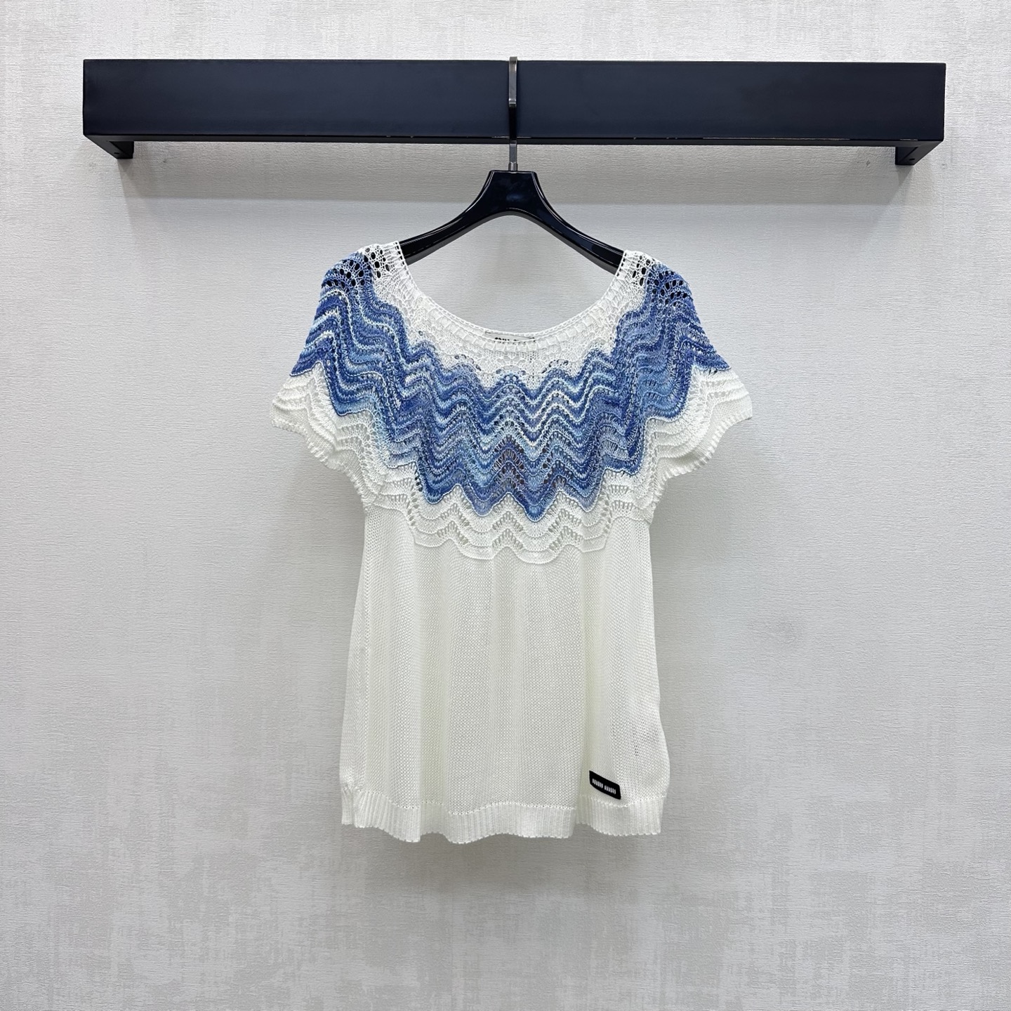 NO:845268,Miumi*2026 new products are on the shelves. Lace splicing round neck short-sleeved knitted custom YB imported blended wool fabric. Lightweight and breathable texture. Soft and skin-friendly. Classic pure white background. Combined with blue and white gradient wave pattern hollow lace splicing design from the shoulder to the neckline to add layering to the look. The hem is embellished with iconic letters and micro-marks to highlight the brand's tone. Create a romantic and fairy feeling. Development of surface accessories. Cutting of round neck slim-fitting short-sleeved tops.  Wear it casually with skirts and trousers, and you can easily create a French resort style. High version, miumiu, skirts, T-shirt,19860909Miumi*2026新品上架蕾丝拼接圆领短袖针织定制YB进口混纺羊毛面料 质地轻盈透气 触感软糯亲肤 经典纯白底色 配合肩部至领口蓝白渐变波浪纹镂空蕾丝拼接设计 增添造型层次感 下摆点缀标志性字母微标装饰 彰显品牌调性 打造浪漫与仙气感 面辅料开发 圆领修身短袖上衣剪裁 随意搭配裙裤装穿搭 都能轻松打造法式度假风   高版本,,miumiu,skirts,T-shirt,,Women's clothing