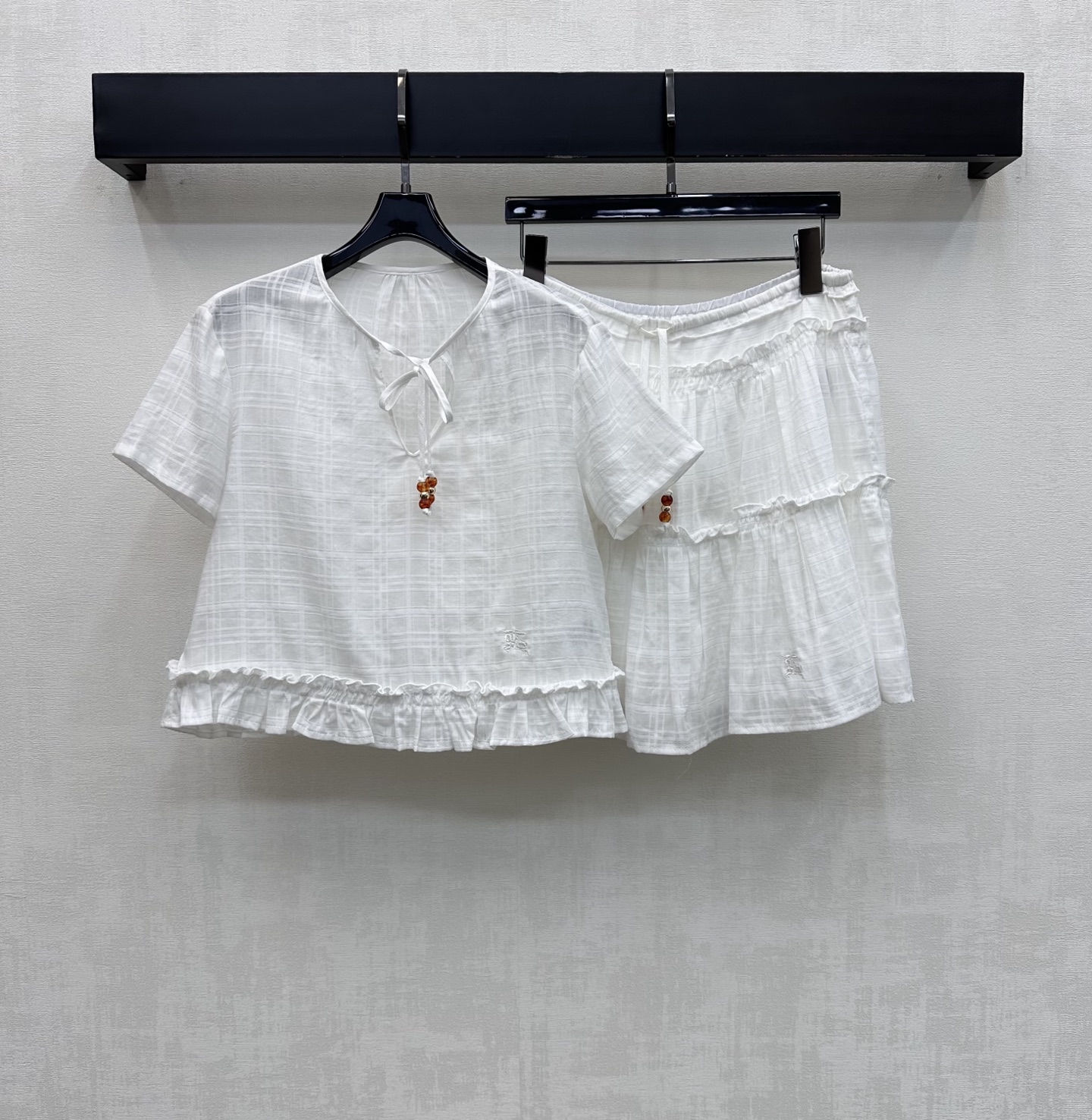 NO:866510,Bur BBR*2026 new product on the shelves. Ruffled lace-up short-sleeved suit customized with YB imported cotton and linen blended fabric. Lightweight and breathable, soft to the touch and skin-friendly. With a slight natural texture. V-neck lace adjustment design to modify the neck line and add layering to the look. Iconic war horse embroidery logo embellishment to highlight the brand tone. Development of fabric accessories. Short top with elastic waist skirt suit. The upper body is elongated and the legs are proportionally taller and slimmer.  The hem of the top and the hems of the shorts are all cut with ruffles to create a sweet and dynamic feel. Wear it in a French resort style. High version, burberry, skirts, shorts, T-shirt,19860909Bur BBR*2026 新品上架荷叶边系带短袖套装定制YB进口棉麻混纺面料 质地轻盈透气 触感柔软亲肤 带有微微自然肌理感 配合V领系带调节设计修饰颈部线条 增添造型层次感 标志性战马刺绣徽标点缀装饰 彰显品牌调性 面辅料开发 短款上衣搭配松紧腰短裙套装 上身拉长腿部比例显高显瘦 上衣下摆及短裤裤脚均采用荷叶边裁剪处理 打造甜美灵动感 穿搭出法式度假风  高版本,,burberry,skirts,shorts,T-shirt,,Women's clothing