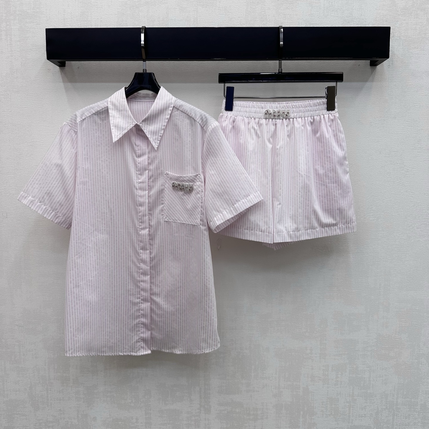 NO:908313,Miumi*2026 new product launch striped shirt shorts suit customized YB imported twill cotton material, light and breathable texture, moisture-wicking, using the lapel to hide the placket button adjustment design, combined with the fresh pink and white stripe elements throughout the body, silver-tone shimmering texture, adding layering to the look. The chest is embellished with the iconic diamond-encrusted letter logo and the waistband is decorated with the same details to highlight the brand tone. Development of surface and accessories. Lapel short-sleeved shirt, elastic waist, shorts tailoring, complete upper body to cover the flesh and make you look slimmer.  Refreshing and high-end to wear for daily dates or vacations, with a sweet and ladylike temperament. High version,,miumiu,shorts,shirts,T-shirt,19860909Miumi*2026新品上架条纹衬衣短裤套装定制YB 进口斜纹棉材质 质地轻盈透气 吸湿排汗 沿用翻领隐藏开襟纽扣调节设计配合通体清新粉白条纹元素银调细闪肌理 增添造型层次感 胸前点缀标志性镶钻字母徽标裤腰同样细节装饰 彰显品牌调性 面辅料开发 翻领短袖衬衫松紧腰短裤剪裁 成套上身遮肉显瘦 日常约会还是度假穿搭清爽高级 自带甜美淑女气质 高版本,,miumiu,shorts,shirts,T-shirt,,Women's clothing