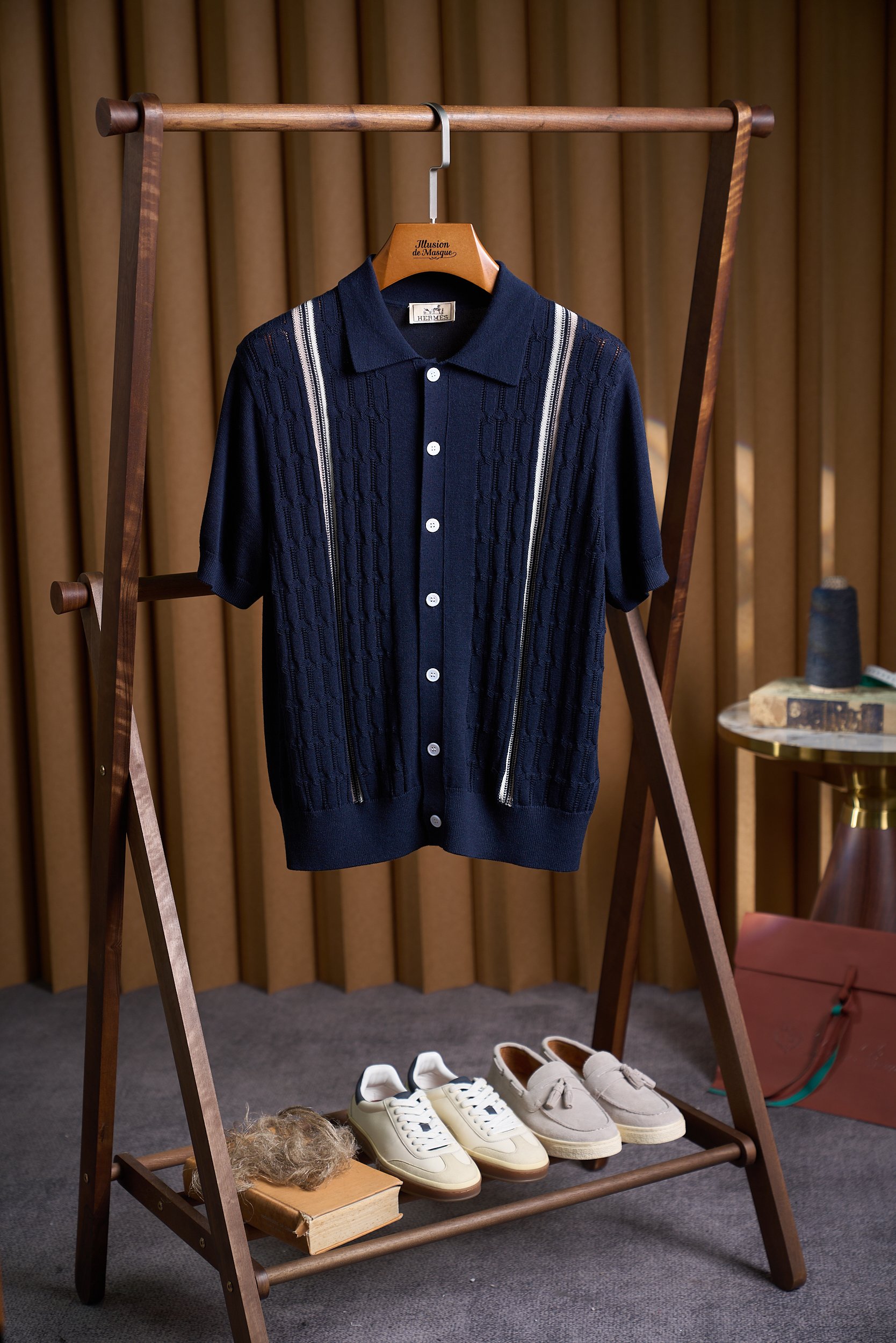 NO:847331,[HM Saddle Weave Three-dimensional Cable Texture Breasted Sweater] This is woven using the brand's iconic saddle stitch (Saddle Stitch) combined with three-dimensional cable craftsmanship, showing the essence of hand-knitting inherited by the brand. The following is a specific process analysis. 1. The fusion of the core technology saddle stitch and three-dimensional cable knitting 1. Saddle Stitch (Saddle Stitch)  As HM's signature handcraft, the saddle stitch method uses double needles and double threads to knit in reverse to form uniform wavy stitches on both front and back sides. It not only visually presents a delicate texture, but also enhances the stretch resistance and durability of the fabric. In the collar, placket and shoulder stripe decoration, you can see the contrasting stitches using this process. The stitches are tight and elastic, and are more three-dimensional than ordinary plain stitches. 2. Three-dimensional cable knitting  The main part uses an 8-pin cable unit, which forms a geometric diamond texture through cross-winding of coils. Every 10 rows form a cycle, giving the fabric a relief-like concave and convex texture. Fine hollow stitches (such as the 'field' plaid) are interspersed between the cables to improve breathability and are suitable for summer wear. 2. Craftsmanship details and materials The material combination is cotton thread as the base, blended with 10 mulberry silk to enhance the luster. The yarn is treated with combing technology, making it delicate and non-frizzy to the touch.  The splicing process uses double stitching on the shoulders and sides of the placket to enhance structural stability; the ribbed edges on the cuffs and hem are woven alternately with plain stitches and purl stitches to ensure an elastic fit. Button details Mother-of-pearl buttons echo the knitted texture, and overlock reinforcement stitching is used around the button holes to avoid deformation caused by repeated wearing and taking off. 3. Washing and maintenance recommendations 1. Washing method  It is recommended to hand wash gently in cold water below 30℃, use neutral detergent, and avoid machine washing and spin-drying; wash dark and light colors separately to prevent the contrasting stitches of the saddle stitch from fading. 2. Drying and ironing: Lay flat to dry in the shade, avoid direct sunlight; if ironing is required, choose low-temperature steam mode (below 110℃), iron the twisted parts with a cloth, and retain the three-dimensional texture. 3. Storage  Hang and store in a ventilated place to avoid twist deformation caused by heavy folding; for long-term storage, you can put anti-moth agent to prevent moth damage. Size M-3XL,,19860909【HM马鞍织法立体绞花纹理排扣针织衫】 这款采用品牌标志性的马鞍针法（Saddle Stitch）结合立体绞花工艺织造,展现品牌传承的手工编织精髓.以下是具体工艺解析 一、核心工艺马鞍针法与立体绞花的融合 1. 马鞍针法（Saddle Stitch） 作为HM标志性手工技艺,马鞍针法通过双针双线反向编织,形成正反两面均匀的波浪形线迹,不仅视觉上呈现细腻纹理,更增强了面料的抗拉伸性与耐用性.在衣领、门襟及肩部条纹装饰处,可见撞色线迹采用该工艺,线迹紧密且富有弹性,与普通平针相比更显立体层次. 2. 立体绞花编织 主体部分采用8针绞花单元,通过线圈交叉缠绕形成几何菱形纹理,每10排为一个循环,使面料呈现浮雕般的凹凸质感.绞花之间穿插细密的镂空针脚（如“田”字格纹）,提升透气性,适配夏季穿着. 二、工艺细节与材质  材质组合棉线为基底,混纺10桑蚕丝提升光泽感,纱线经精梳工艺处理,触感细腻不毛躁.  拼接工艺肩部、门襟侧边采用双线辑明线,强化结构稳定性；袖口与下摆的罗纹收边则通过平针与反针交替编织,确保弹性贴合.  纽扣细节珍珠母贝纽扣与针织纹理呼应,纽扣孔周围采用锁边加固针法,避免反复穿脱导致变形. 三、洗涤养护建议 1. 洗涤方式  建议30℃以下冷水轻柔手洗,使用中性洗涤剂,避免机洗甩干；  深浅色分开洗涤,防止马鞍针法的撞色线迹褪色. 2. 晾晒与熨烫  平铺阴干,避免阳光直射；如需熨烫,选择低温蒸汽模式（110℃以下）,垫布熨烫绞花部位,保留立体纹理. 3. 收纳  悬挂存放于通风处,避免折叠重压导致绞花变形；长期存放可放入防蛀剂,防止虫蛀. 码数M-3XL,,,Men's clothing