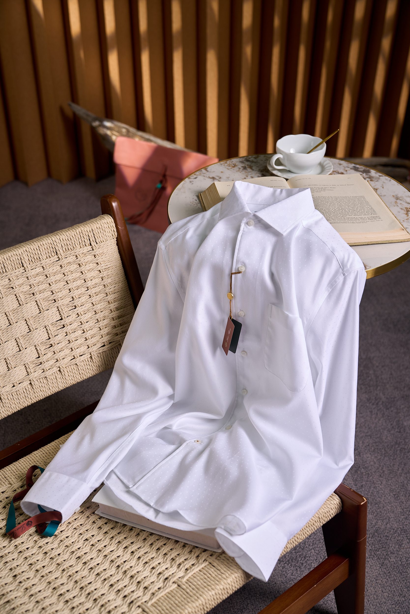 NO:911541,[Daily luxury of Noyo Panya pure cotton jacquard business shirt with Italian precision craftsmanship] 1. The pinnacle of brand genes and centuries-old cotton spinning craftsmanship  As Italy's top luxury fabric family, Noyo Piana is famous for its 'ultimate pursuit of natural materials.' This shirt is made from Egyptian long-staple cotton, with a fiber length of 38mm, and is spun into 120-count double-ply yarn on a Swiss Rieter spinning machine. It feels as delicate as silk, while retaining the natural breathability and stiffness of cotton. The fabric has passed OEKO-TEX certification and contains no chemical residues, so sensitive skin can be worn with peace of mind. 2. Design highlights: low-key jacquard business aesthetics  1. Geometric jacquard dark pattern The fabric uses 16 stitches/cm precision jacquard technology to weave a 0.3cm square diamond-shaped dark pattern. It appears pure white from a distance and has a hidden three-dimensional texture when viewed up close. It shows low-key taste in business situations. The jacquard pattern is derived from the equestrian silk scarf pattern of the 1960s in the brand archives, giving the classic item a retro heritage. 2. Italian tailoring details  The Windsor collar has a tip angle of 120°, suitable for ties or worn alone. The collar lining uses a 3-layer composite process to ensure that it does not deform after long-term wear. The three-dimensional darts have hidden 2cm darts on both sides of the waist to optimize the body line; the double pleat structure at the back enhances freedom of movement. The hand-made detailed cuffs adopt a 'French stacked button' design, and the mother-of-pearl buttons are polished by hand. The buttonholes are double-locked, making them durable and not easy to fall off. 3. Functional design  Hidden pockets. There is a secret pocket for mobile phone storage sewn on the inside of the left breast pocket. 4. Washing and maintenance guide 1. Washing method: Gentle machine wash using neutral laundry detergent, the water temperature does not exceed 40℃, put it in the laundry bag and select 'gentle mode' to avoid deformation of the jacquard texture. Wash separately in cold water before wearing for the first time, add a small amount of white vinegar to fix the color; wash dark and light colored clothes separately to prevent staining. 2. Drying and ironing  Hang in a ventilated place to dry in the shade to avoid direct sunlight causing yellowing of the fabric; pat the collar lightly after drying to restore stiffness. For low-temperature ironing, choose steam ironing below ℃. During ironing, place a cloth to protect the jacquard pattern. The collar lining can be properly sprayed with water to shape it. 3. Storage recommendations: Use a wide-shoulder hanger for hanging, and place a paper at the neckline to prevent deformation; when storing for a long time, use anti-moth agent to avoid the growth of mold in a humid environment.  Noyo Panya's shirts take 'everyday luxury' as the core. Each piece is handmade in the Biella factory in Italy. Through the ultimate polishing of materials and craftsmanship, business attire is sublimated from 'necessity' to 'an expression of taste.' Just like the brand's century-old philosophy, 'True luxury is to make comfort and elegance become everyday.' Size M-3XL, shirts, ties,19860909【诺悠翩雅纯棉提花商务衬衫意式精密工艺的日常奢华】 一、品牌基因百年棉纺工艺的巅峰之作 作为意大利顶奢面料世家,诺悠翩雅以「对天然材质的极致追求」闻名.这款衬衫甄选埃及长绒棉,纤维长度达38mm,经瑞士立达纺纱机精纺成120支双股纱线,触感如丝绸般细腻,同时保留棉天然的透气性与挺括度.面料通过OEKO-TEX认证,不含化学残留,敏感肌亦可安心穿着. 二、设计亮点低调提花的商务美学 1.几何提花暗纹 面料采用16针/厘米精密提花工艺,织就0.3cm见方的菱形暗纹,远观呈现纯净白色,近看则暗藏立体肌理,在商务场合中低调彰显品味.提花图案源自品牌档案馆1960年代马术丝巾纹样,赋予经典单品复古底蕴. 2.意式剪裁细节  温莎领型领尖夹角120°,适配领带或单独穿着,领衬采用3层复合工艺,确保久穿不变形.  立体收省腰部两侧暗藏2cm收省设计,优化身形线条；后幅双褶结构,增强活动自由度.  手工细节袖口采用「法式叠扣」设计,珍珠母贝纽扣经手工打磨,扣孔处双线锁边,耐穿不易脱线. 3.功能性设计  隐藏式口袋左侧胸前口袋内侧缝有手机收纳暗袋. 四、洗涤养护指南 1.洗涤方式  轻柔机洗使用中性洗衣液,水温不超过40℃,放入洗衣袋选择「轻柔模式」,避免提花纹理变形.  单独洗涤首次穿着前单独冷水洗涤,加入少量白醋固色；深浅色衣物分开洗,防止染色. 2.晾晒与熨烫  阴干处理悬挂于通风处阴干,避免阳光直射导致面料泛黄；晾干后轻拍领部,恢复挺括度.  低温熨烫选择℃以下蒸汽熨烫,熨烫时垫布保护提花图案,领衬处可适当喷水定型. 3.收纳建议  使用宽肩衣架悬挂,领口处垫纸防止变形；长期存放时,搭配防蛀剂,避免潮湿环境滋生霉菌. 诺悠翩雅的衬衫以「日常奢华」为核心,每一件都在意大利比耶拉工厂手工完成,通过对材质与工艺的极致打磨,让商务着装从「必要」升华为「品味的表达」.正如品牌传承百年的理念「真正的奢侈,是让舒适与优雅成为日常」. 码数M-3XL,,shirts,ties,,Men's clothing