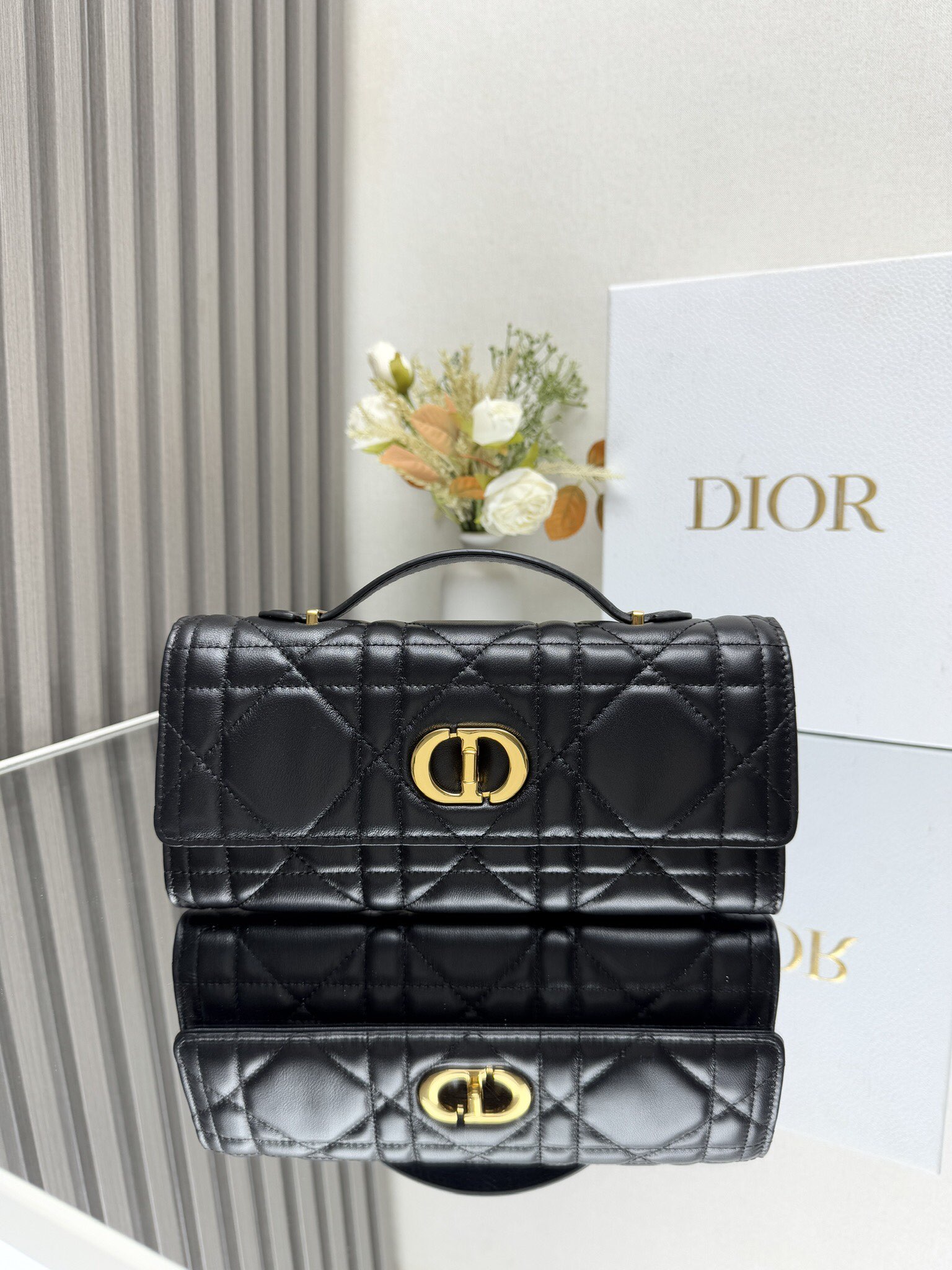 NO:204765,Miss Caro Top Handle clutch Black sheep leather oversized rattan check Model: 5221 This Miss Caro Top Handle clutch is a new product in the early spring series of 2025. It is a daily item that highlights the exquisite charm. It is carefully crafted from black sheep leather, decorated with oversized rattan checked thread, and the flip is decorated with retro gold finish metal knob CD buckle. It is inspired by the seal of the Christian Dior perfume bottle, and it is paired with a compartment to store a variety of daily necessities. It is paired with a foldable top handle, which can be carried and enhances the exquisite appearance. Material fabric sheep leather lining sheepskin, leather fabric knob CD buckle Flip opening and closing 1 internal compartment 1 insert bag 6 slots  Foldable leather top handle Included dust bag Size 24 x 12 x 4 cm (L x H x W) Can hold 1 card clip and 1 mobile phone, Dior, Dior, Dior, Handbag, Sheepskin19860909Miss Caro Top Handle 手拿包 黑色羊皮革超大藤格纹 型号: 5221 这款 Miss Caro Top Handle 手拿包是二零二五早春系列新品,是一款彰显精致魅力的日常单品.采用黑色羊皮革精心制作,饰以超大藤格纹缉面线,翻盖饰以复古金色饰面金属旋钮式 CD 扣环,灵感源自 Christian Dior 香水瓶的封口,搭配一个隔层,可收纳各种日常用品.搭配可折叠的顶部手柄,可手提,提升精致外观. 材质面料羊皮革 里料羊皮,革织物 旋钮式 CD 扣环 翻盖开合 1 个内部隔层 1 个插袋 6 个卡槽 可折叠的皮革顶部手柄 内含防尘袋 尺寸24 x 12 x 4 厘米（长 x 高 x 宽） 可收纳 1 个卡夹和 1 部手机,迪奥,dior,dior,handbag,sheepskin,Bag