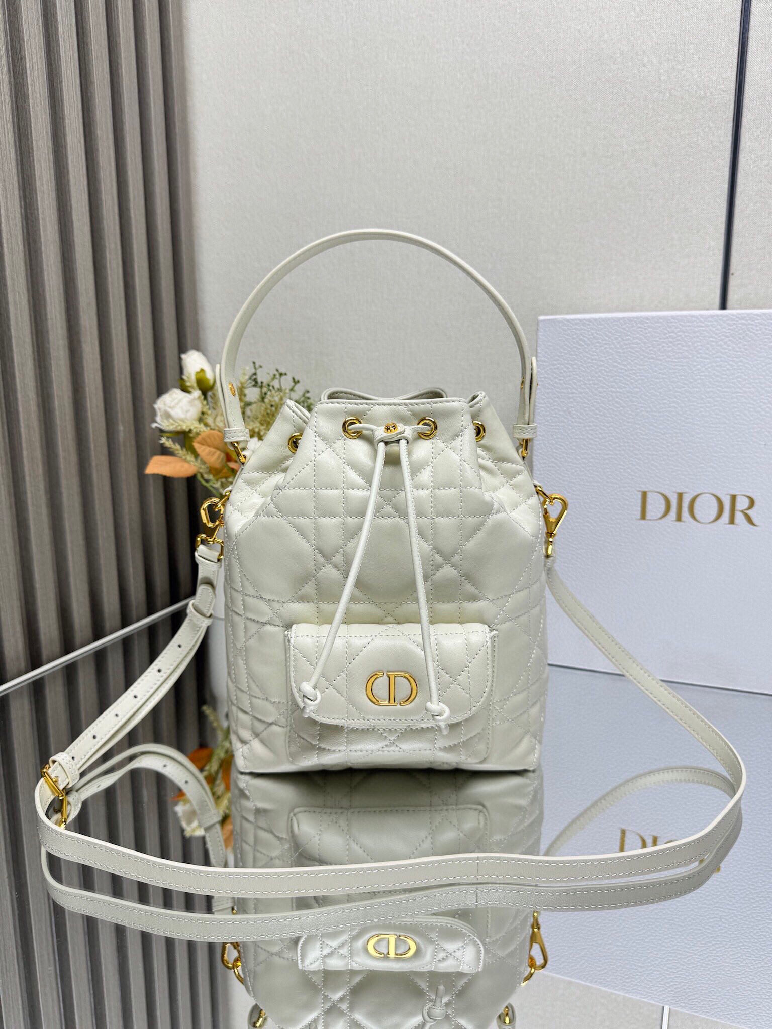 NO:659353,This Dior Caro bucket bag is a new product in the 2025 autumn ready-to-wear series, highlighting a fashionable and elegant style. It is carefully made of black sheepskin and other materials, decorated with oversized cannage pattern topstitching, and has a spacious drawstring compartment. The front flap pocket is decorated with a gold-finished metal CD logo, which can store various small daily necessities. The small style is equipped with a removable top handle and an adjustable and detachable shoulder strap, which can be easily carried by hand, shoulder or crossbody. Main body: sheepskin,  Cow leather lining: cow leather CD logo drawstring closure on the front Front slip pocket with magnetic flap Internal slip pocket Detachable leather handle on top Adjustable, removable leather shoulder strap with dust bag included Model: M3372 off-white Size 20cm*24cm*9cm 000600, Dior, dior, dior, cowhide, sheepskin19860909这款 Dior Caro 水桶包是二零二五秋季成衣系列新品,彰显时尚优雅风范.采用黑色羊皮革等材质精心制作,饰以超大藤格纹缉面线,带有宽敞的抽绳隔层.正面翻盖口袋饰以金色饰面金属CD标志,可收纳各种小件日常用品.小号款式,搭配可拆卸顶部手柄和可调节、可拆卸肩带,可轻松手提、肩背或斜挎. 主体:羊皮革, 牛皮革里料:牛皮革 正面饰以CD 标志抽绳开合 正面插袋搭配磁性翻盖内部插袋 顶部可拆卸皮革手柄 可调节、可拆卸的皮革肩带内含防尘袋 型号:M3372 米白色 尺寸20cm*24cm*9cm 000600,迪奥,dior,dior,cowhide,sheepskin,Bag