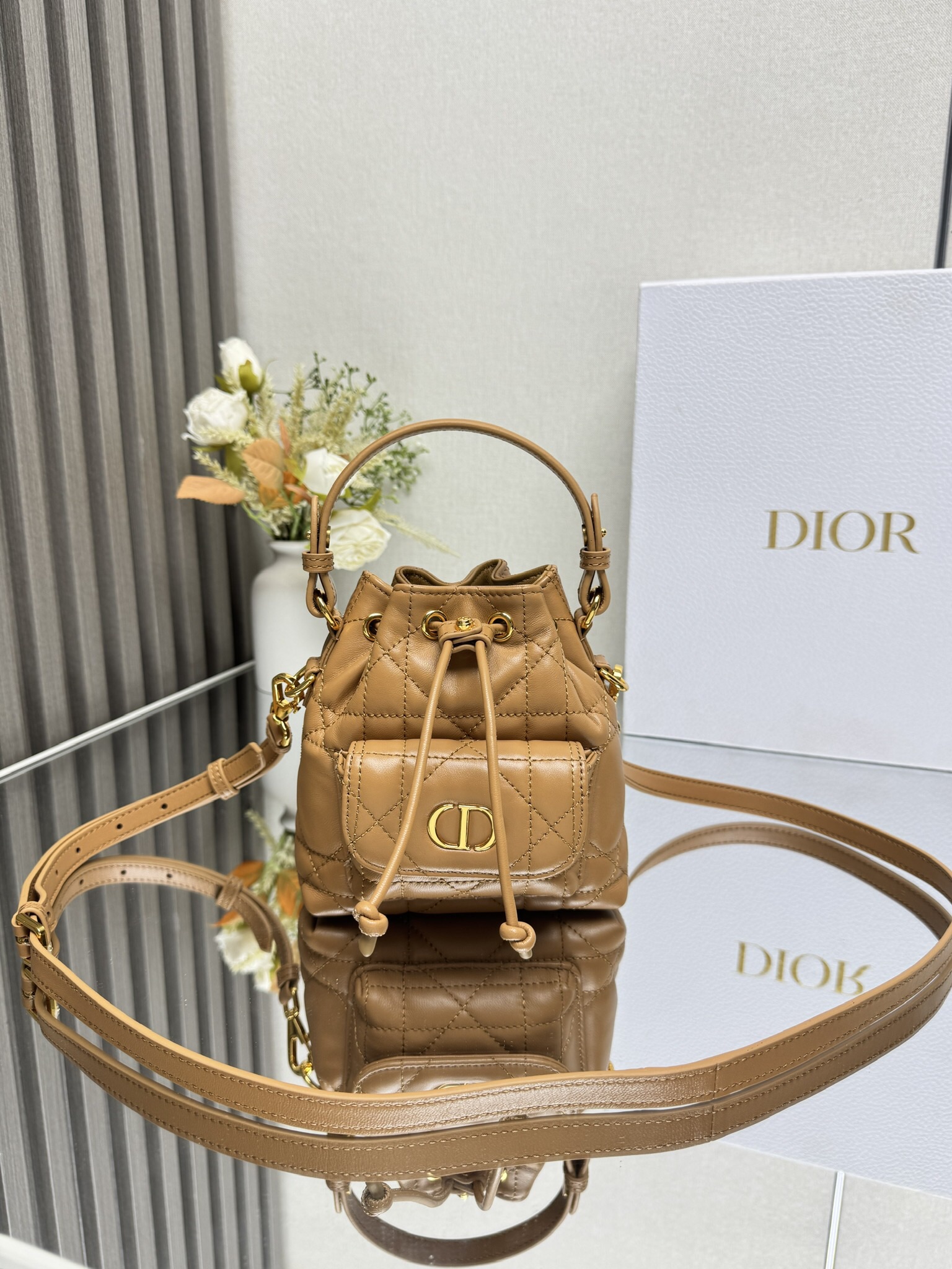 NO:659345,This miniature Dior Caro bucket bag is a new addition to the Fall 2025 ready-to-wear collection, emphasizing fashionable elegance. It is crafted from black sheepskin, decorated with oversized cannage pattern topstitching, and has a drawstring compartment. The front flap pocket is decorated with a vintage gold-finish metal CD logo, which can store a variety of small daily necessities. Fashionable and versatile, with a detachable top handle and an adjustable and detachable shoulder strap, it can be carried by hand, shoulder or cross-body.  CD logo drawstring closure on the front Magnetic flap pocket on the front Internal slip pocket Detachable leather handle on top Adjustable, detachable leather shoulder strap with dust bag included Size 14*15*7cm Made in Italy Model number: Mini khaki 000550, Dior, dior, dior, sheepskin19860909这款微型 Dior Caro 水桶包是二零二五秋季成衣系列新品,彰显时尚优雅风范.采用黑色羊皮革精心制作,饰以超大藤格纹缉面线,设有一个抽绳隔层.正面翻盖口袋饰以复古金色饰面金属CD 标志,可收纳各种小件日常用品.时尚百搭,搭配可拆卸顶部手柄和可调节、可拆卸的肩带,可手提、肩背或斜挎. 正面饰以CD标志抽绳开合 正面磁性翻盖口袋内部插袋 顶部可拆卸皮革手柄 可调节、可拆卸的皮革肩带内含防尘袋 尺寸14*15*7cm 意大利制造 型号: 迷你土黄色 000550,迪奥,dior,dior,sheepskin,Bag