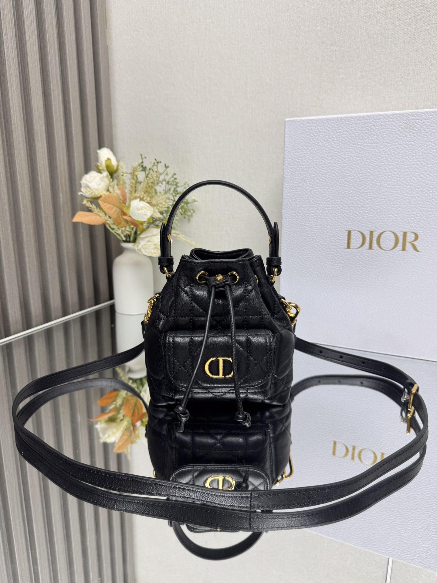 NO:659354,This miniature Dior Caro bucket bag is a new addition to the Fall 2025 ready-to-wear collection, emphasizing fashionable elegance. It is crafted from black sheepskin, decorated with oversized cannage pattern topstitching, and has a drawstring compartment. The front flap pocket is decorated with a vintage gold-finish metal CD logo, which can store a variety of small daily necessities. Fashionable and versatile, with a detachable top handle and an adjustable and detachable shoulder strap, it can be carried by hand, shoulder or cross-body.  CD logo drawstring closure on the front Magnetic flap pocket on the front Internal slip pocket Detachable leather handle on top Adjustable, detachable leather shoulder strap with dust bag included Size 14*15*7cm Made in Italy Model number: mini black 000550, Dior, dior, dior, sheepskin19860909这款微型 Dior Caro 水桶包是二零二五秋季成衣系列新品,彰显时尚优雅风范.采用黑色羊皮革精心制作,饰以超大藤格纹缉面线,设有一个抽绳隔层.正面翻盖口袋饰以复古金色饰面金属CD 标志,可收纳各种小件日常用品.时尚百搭,搭配可拆卸顶部手柄和可调节、可拆卸的肩带,可手提、肩背或斜挎. 正面饰以CD标志抽绳开合 正面磁性翻盖口袋内部插袋 顶部可拆卸皮革手柄 可调节、可拆卸的皮革肩带内含防尘袋 尺寸14*15*7cm 意大利制造 型号: 迷你黑色 000550,迪奥,dior,dior,sheepskin,Bag