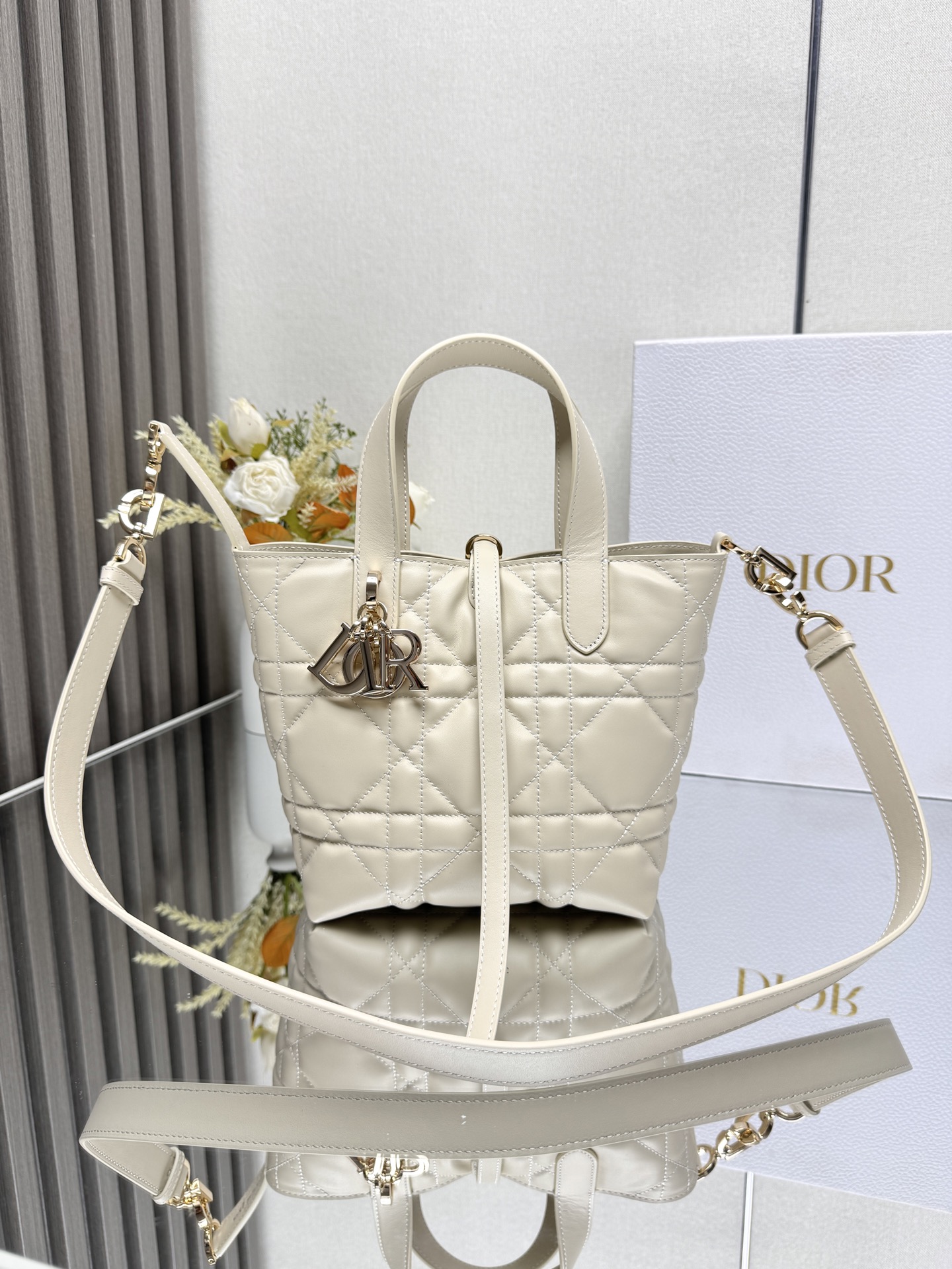 NO:855150,This Dior Toujours vertical handbag is a new product in the 2025 early spring ready-to-wear series. It is fashionable, practical and unique. It is carefully made of ivory white cow leather and decorated with oversized cannage pattern topstitching. The spacious internal compartment can store a variety of daily necessities. It has a slim leather lace closure to safely store various items, and there is a CD Lock  Letter D knob-type buckle, adjustable on both sides, enhances style. Small style, top leather handle with detachable leather shoulder strap, can be carried by hand, shoulder or cross-body. Main body: cow leather. Lining: cow leather. Size 16×18×12cm. Style number 23865, Dior, dior, dior, cowhide.19860909这款 Dior Toujours竖版手袋是二零二五早春成衣系列新品,时尚实用,别具一格.采用象牙白色牛皮革精心制作,饰以超大藤格纹缉面线,宽敞的内部隔层可收纳各种日常用品.设有纤细皮革系带开合,可安全收纳各种物品,另有CD Lock 字母D旋钮式扣环,可调节两侧,提升格调.小号款式,顶部皮革手柄搭配可拆卸的皮革肩带,可手提、肩背或斜挎 主体:牛皮革里料:牛皮革 尺寸16×18×12cm 款号 23865,迪奥,dior,dior,cowhide,Bag