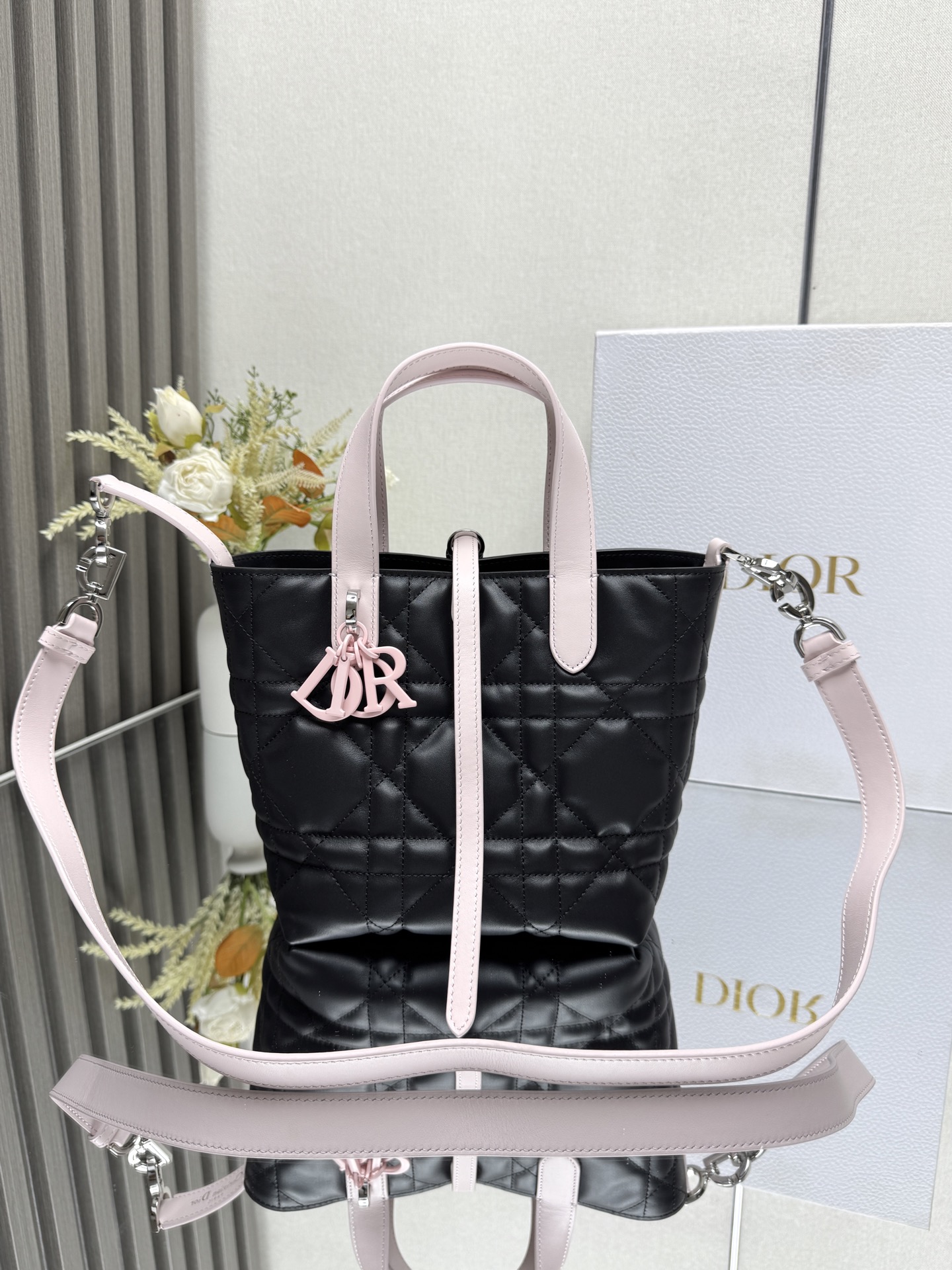 NO:940981,This Dior Toujours vertical handbag is a new product in the 2025 early spring ready-to-wear series. It is fashionable, practical and unique. It is carefully made of black and pink cow leather and decorated with oversized cannage pattern topstitching. The spacious internal compartment can store a variety of daily necessities. It has a slim leather lace closure to safely store various items, and there is a CD Lock  Letter D knob-type buckle, adjustable on both sides, enhances style. Small style, top leather handle with detachable leather shoulder strap, can be carried by hand, shoulder or cross-body. Main body: cow leather. Lining: cow leather. Size 16×18×12cm. Style number, Dior, dior, dior, cowhide.19860909这款 Dior Toujours竖版手袋是二零二五早春成衣系列新品,时尚实用,别具一格.采用黑配粉色牛皮革精心制作,饰以超大藤格纹缉面线,宽敞的内部隔层可收纳各种日常用品.设有纤细皮革系带开合,可安全收纳各种物品,另有CD Lock 字母D旋钮式扣环,可调节两侧,提升格调.小号款式,顶部皮革手柄搭配可拆卸的皮革肩带,可手提、肩背或斜挎 主体:牛皮革里料:牛皮革 尺寸16×18×12cm 款号,迪奥,dior,dior,cowhide,Bag