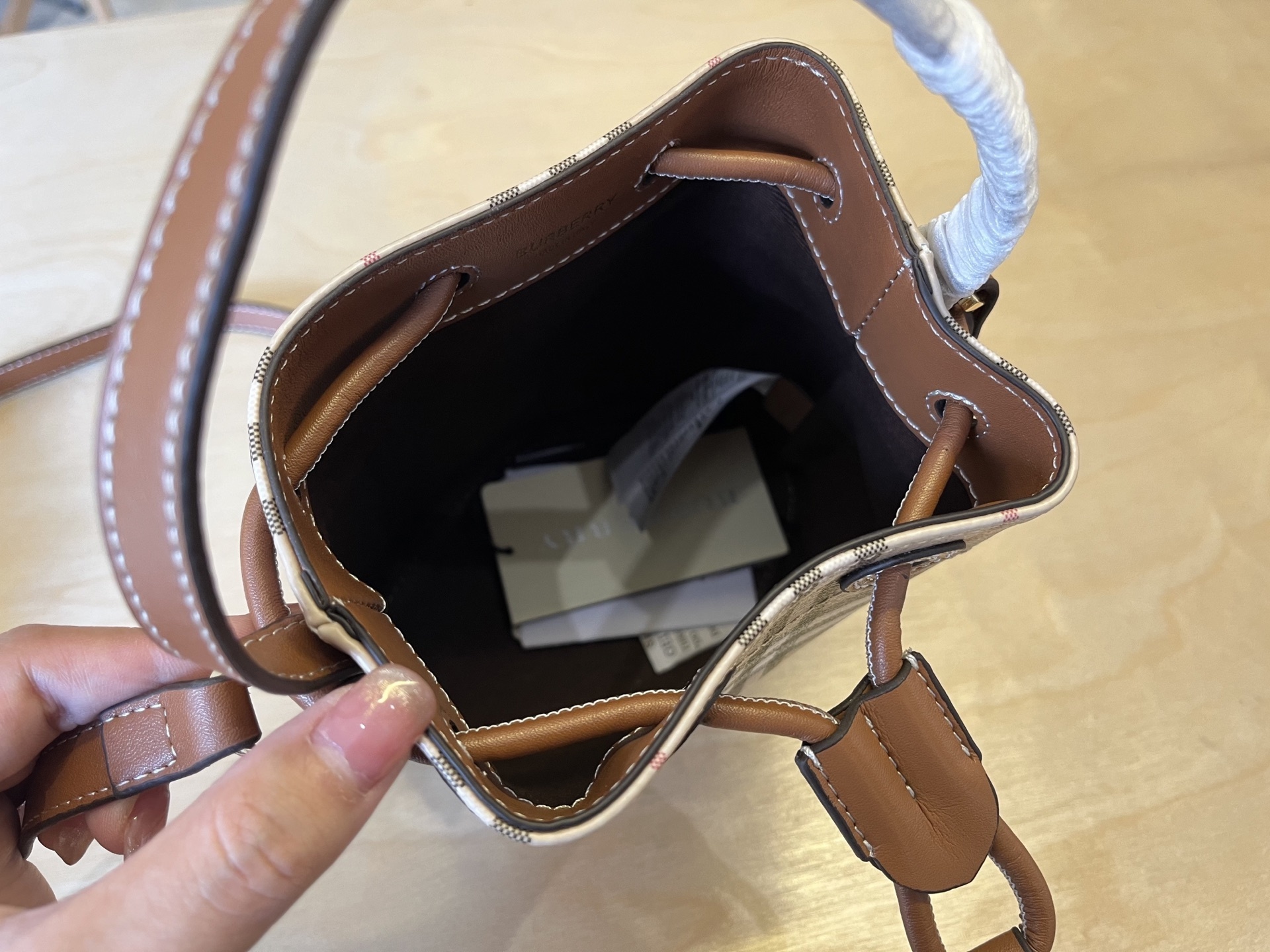 B家小迷你抽绳水桶包,装饰 Burberry 格纹,搭配意大利鞣制皮革边饰和 TB 专属标识。11、16
