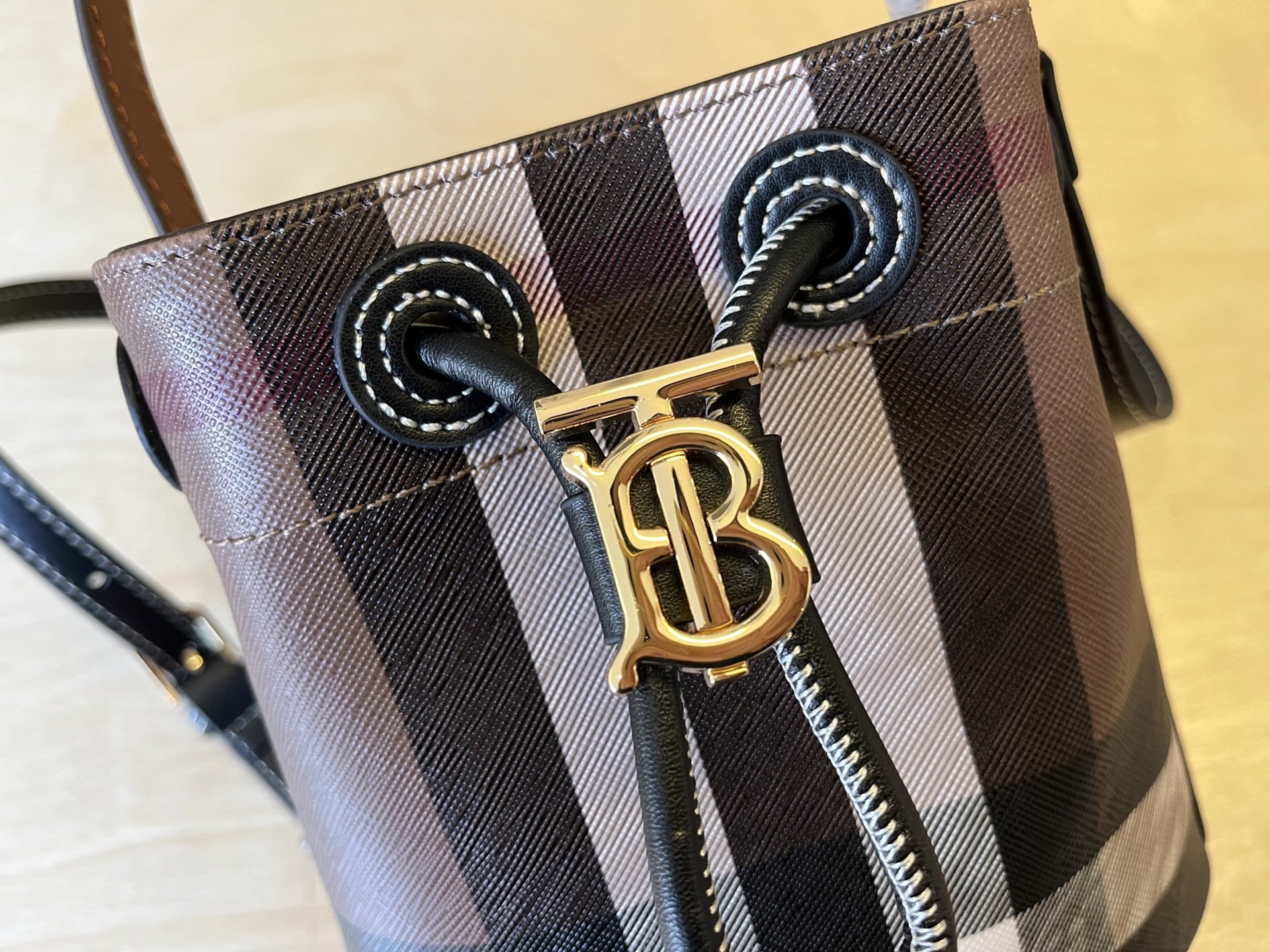 B家小迷你抽绳水桶包,装饰 Burberry 格纹,搭配意大利鞣制皮革边饰和 TB 专属标识。11、16