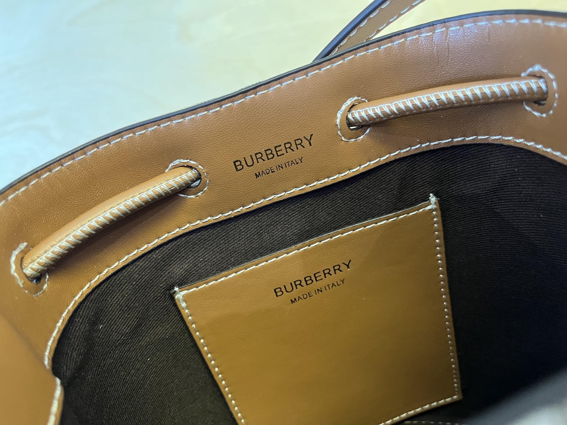B家小迷你抽绳水桶包,装饰 Burberry 格纹,搭配意大利鞣制皮革边饰和 TB 专属标识。11、16