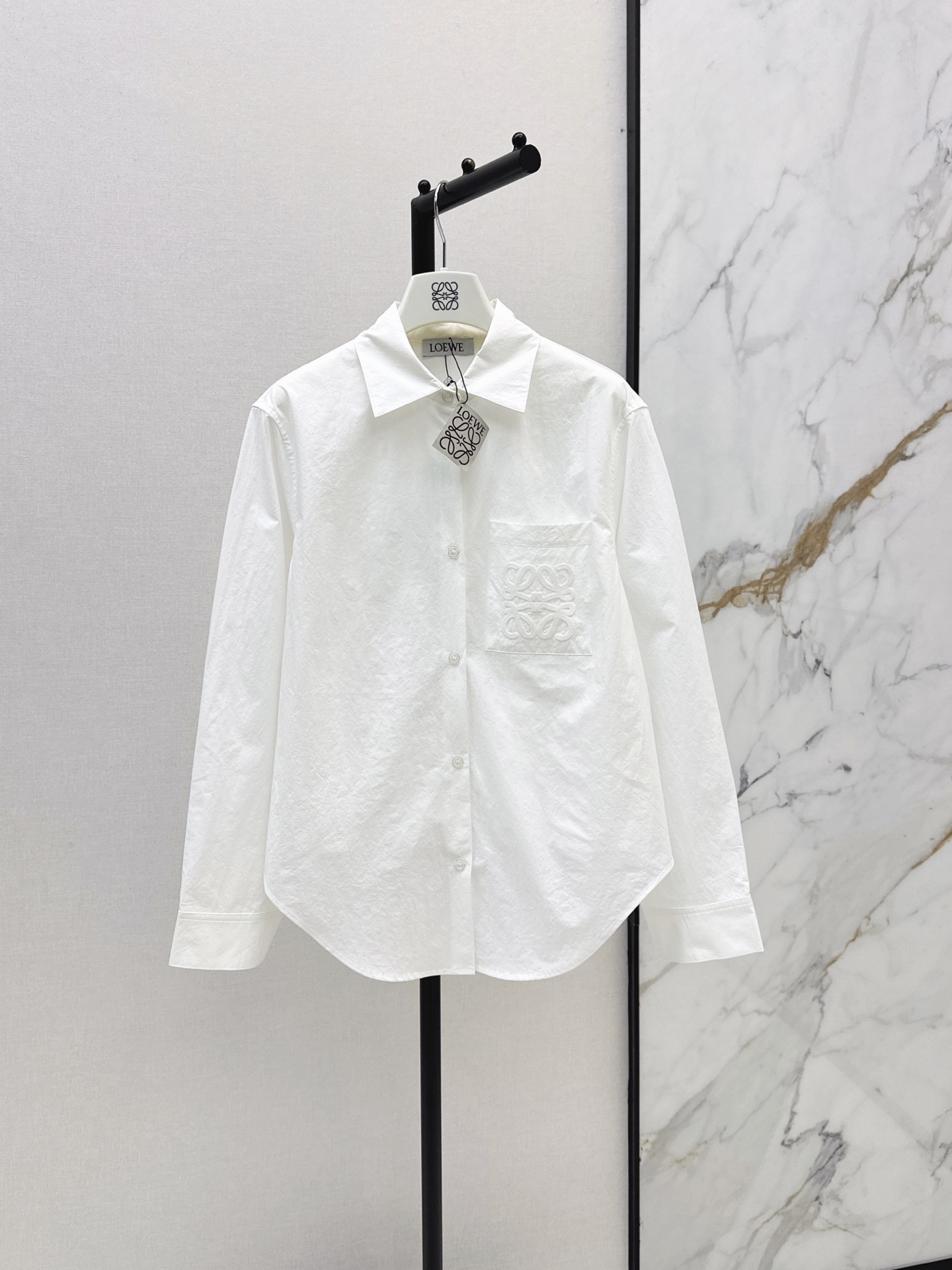 NO:892922,Loe 26Ss - the latest spring and summer minimalist and relaxed style with a classic logo embroidered lapel shirt. Irregular hem tailoring creates a loose A-line silhouette. The back is draped and elegant. The light and slightly wrinkled breathable cotton fabric has a soft texture. The three-dimensional version is not attractive. British neutral style pocket embroidery logo is low-key and luxurious. It is versatile for commuting and the upper body is super slim. It interprets lazy and casual high-end items. Two-color sml,, loewe, shirts,19860909Loe 26Ss————春夏最新款极简松弛感穿搭经典徽标刺绣翻领衬衫 不规则下摆剪裁打造散摆A字廓形 背面垂坠飘逸 轻薄微皱透气棉质面料自带柔和肌理感 立体版型不挑人 英伦中性风口袋刺绣logo低调奢华 通勤百搭上身超显瘦 演绎慵懒随性的高级单品 两色sml,,loewe,shirts,,Women's clothing