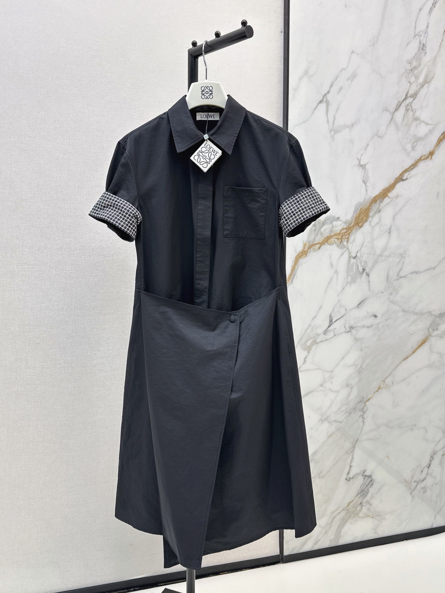 NO:899272,Loe 26Ss - the latest black irregular shirt dress for early autumn. Made of crisp and stylish cotton fabric. Folded plaid short sleeves. Simple pockets on the chest + logo embellishment. Irregular wrapped hem cut and buttoned. The lining is plaid design. The loose fit makes you look slimmer and hides your body. It can be worn for daily commuting, shopping and dating. It is simple and has a sense of design. It can be worn effortlessly to give a sense of intellectual relaxation.  One color smlxl,,loewe,skirts,shirts,T-shirt,19860909Loe 26Ss———早秋最新款黑色不规则衬衫裙 棉质面料挺括有型 翻折格纹短袖 胸前简约口袋+logo点缀 不规则围裹下摆裁剪纽扣固定 内里是格纹设计 宽松版型显瘦藏肉一绝 日常通勤 逛街约会都能穿 简约又有设计感 不费力穿出知性松弛感 一色smlxl,,loewe,skirts,shirts,T-shirt,,Women's clothing