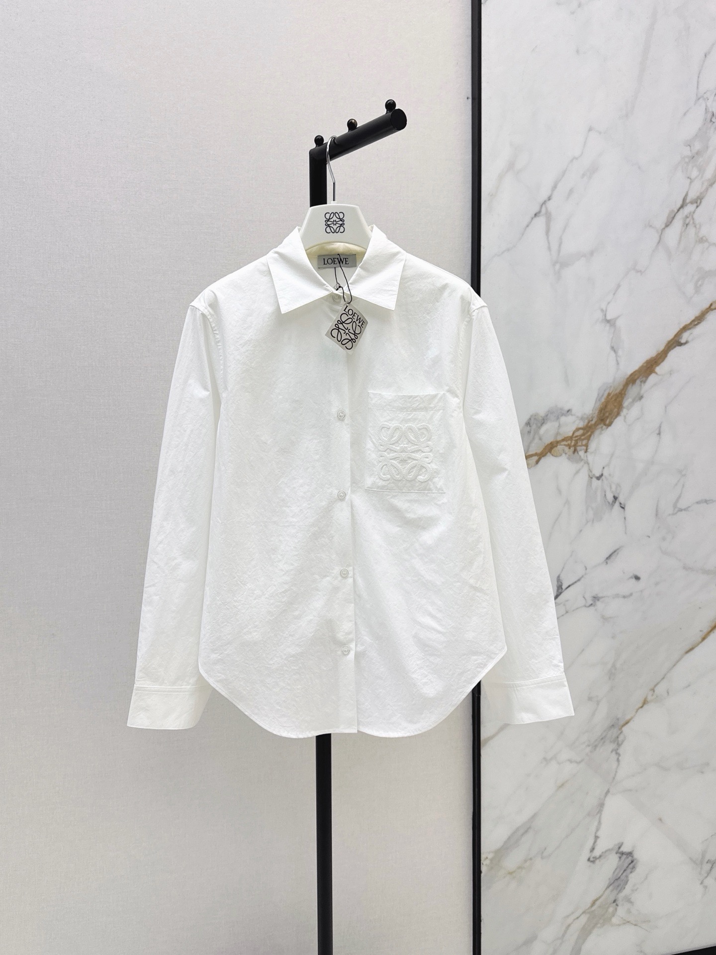 NO:948509,Loe 26Ss - the latest spring and summer minimalist relaxed style classic logo embroidered lapel shirt. Irregular hem cut to create a loose A-line silhouette. The back is draped and elegant. The light and slightly wrinkled breathable cotton fabric has a soft texture. The three-dimensional version is not attractive. British neutral style pocket embroidery logo is low-key and luxurious. It is versatile for commuting and the upper body is super slim. It interprets lazy and casual high-end items. Two-color sml,, loewe, shirts,19860909Loe 26Ss————春夏最新款极简松弛感穿搭经典徽标刺绣翻领衬衫 不规则下摆剪裁打造散摆A字廓形 背面垂坠飘逸 轻薄微皱透气棉质面料自带柔和肌理感 立体版型不挑人 英伦中性风口袋刺绣logo低调奢华 通勤百搭上身超显瘦 演绎慵懒随性的高级单品 两色sml,,loewe,shirts,,Women's clothing