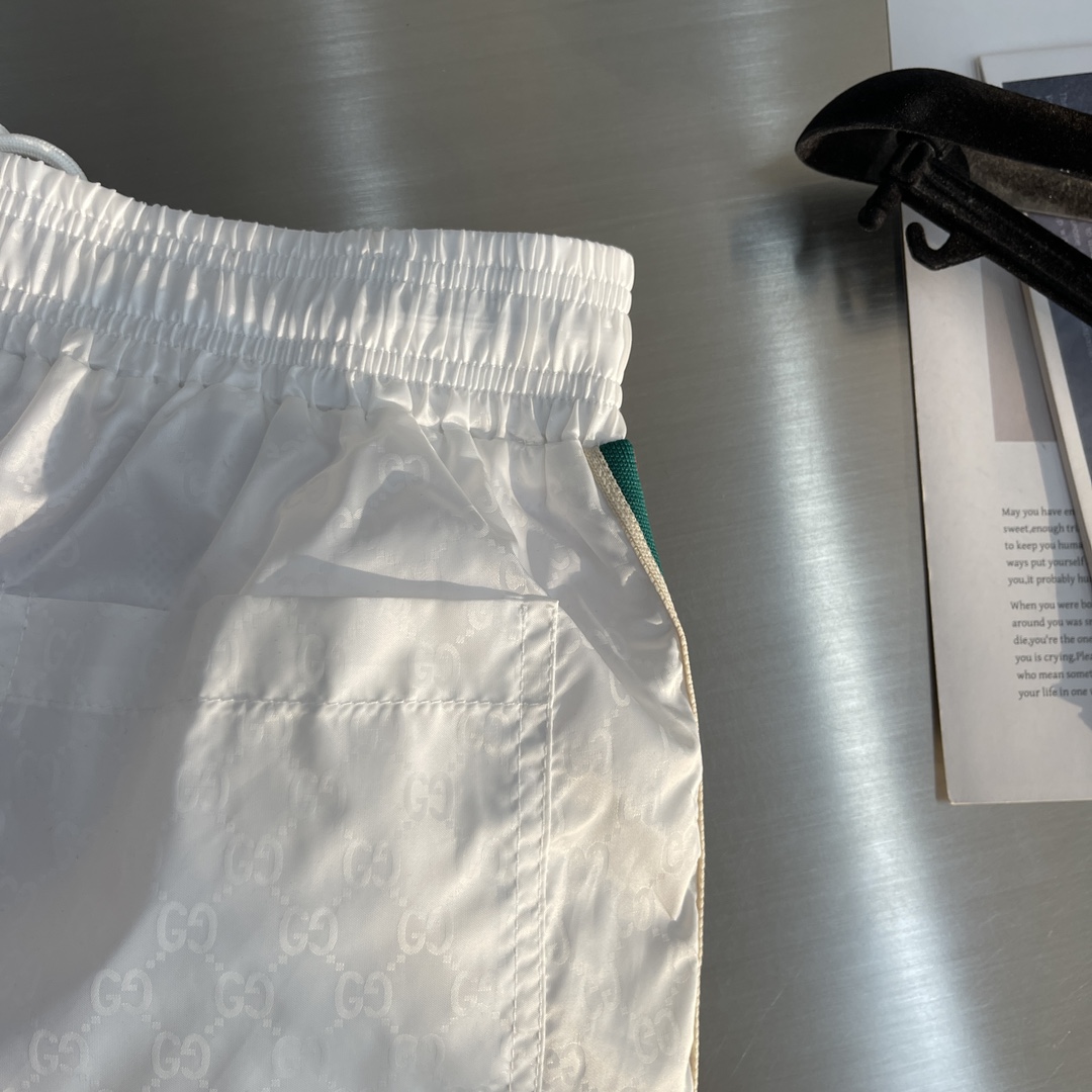 -GUCC 彩边休闲沙滩短裤，这款短裤采用双GG提花面料制作，腰头有松紧腰绳，两个口袋配有拉链，裤腿侧边