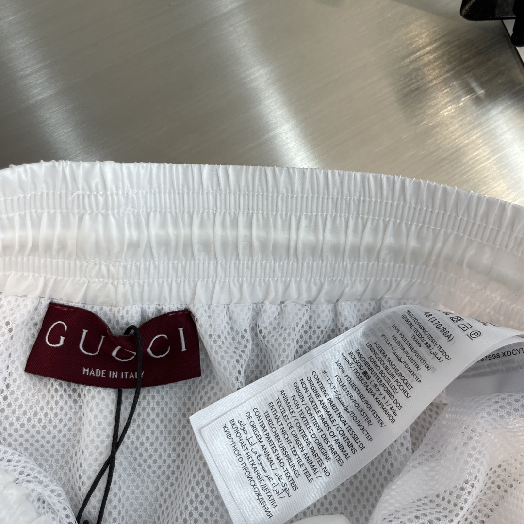 -GUCC 彩边休闲沙滩短裤，这款短裤采用双GG提花面料制作，腰头有松紧腰绳，两个口袋配有拉链，裤腿侧边