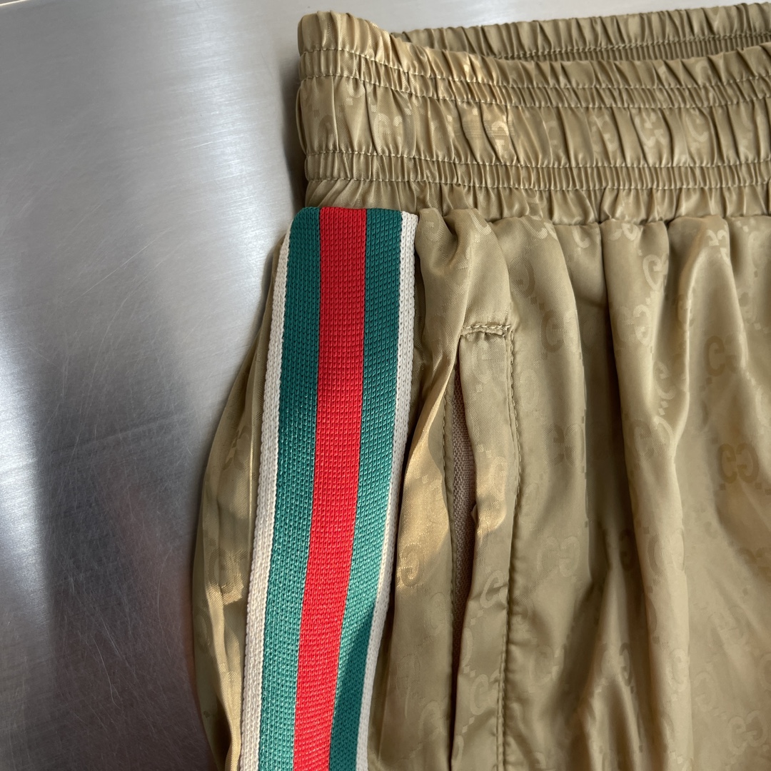 -GUCC 彩边休闲沙滩短裤，这款短裤采用双GG提花面料制作，腰头有松紧腰绳，两个口袋配有拉链，裤腿侧边