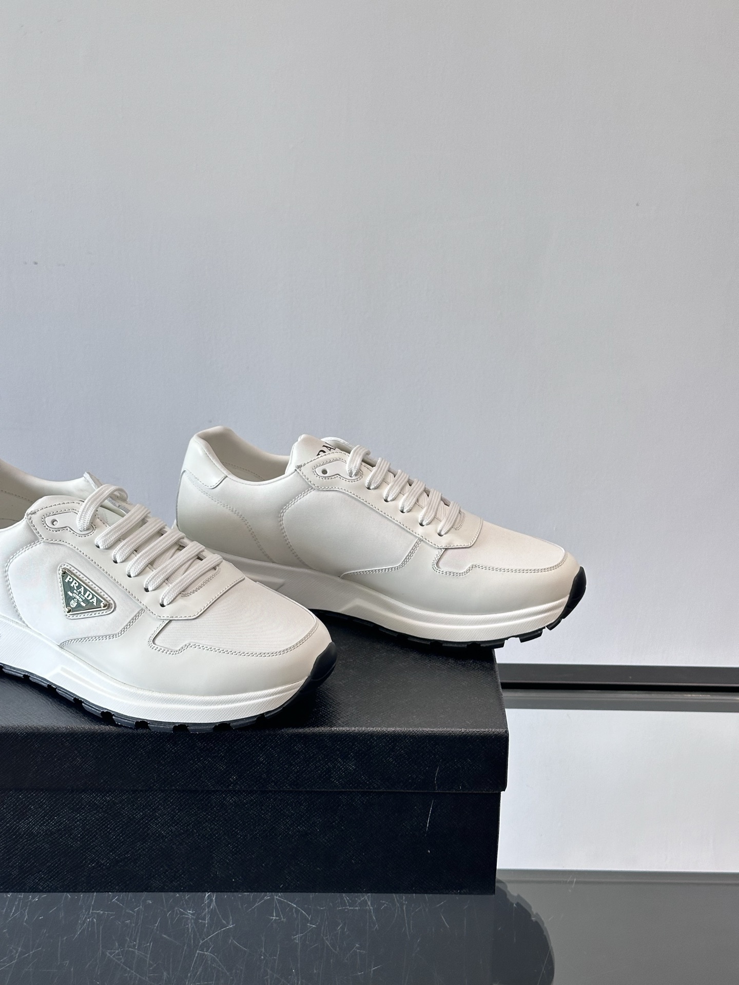 Prada/普拉达 男士新款运动休闲鞋，这款运动鞋鞋面采用进口小牛皮。外侧饰以P家经典金属三角珐琅徽标，